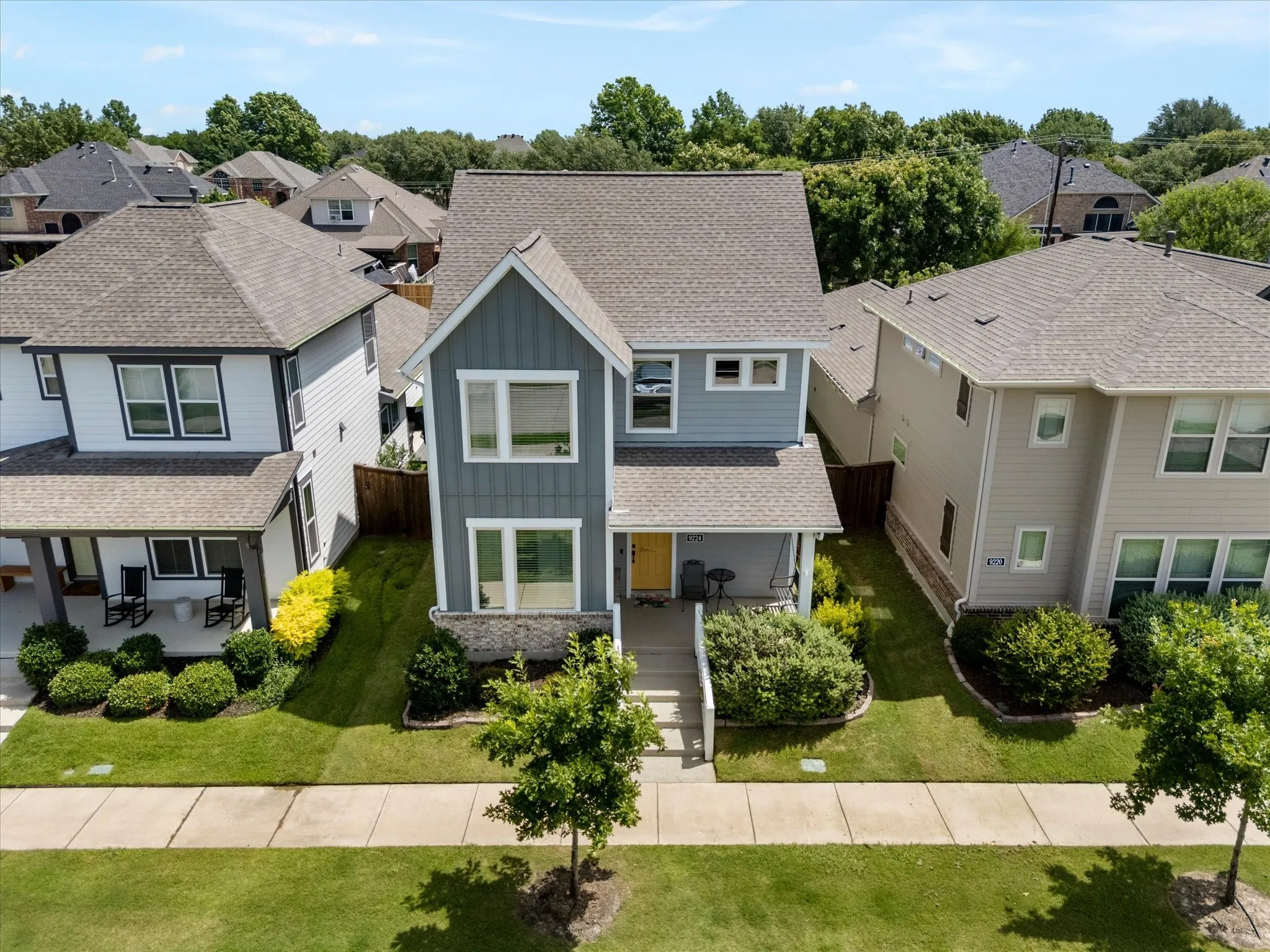 Contemporary two-story exterior with a mixed material facade featuring vertical and horizontal siding, stone accents, and a covered front porch