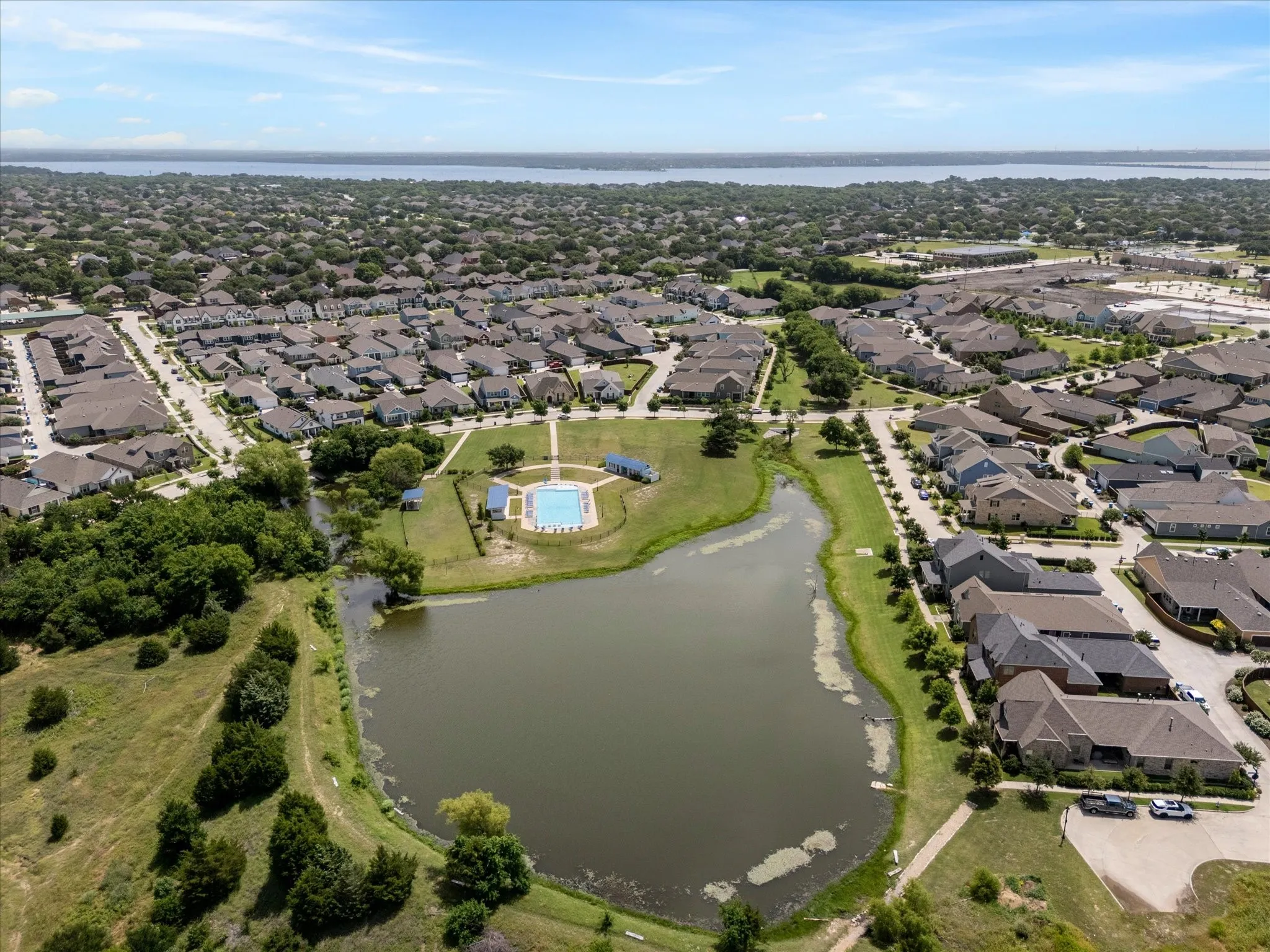 Aerial perspective showcasing a residential community with a central pond and a recreational area