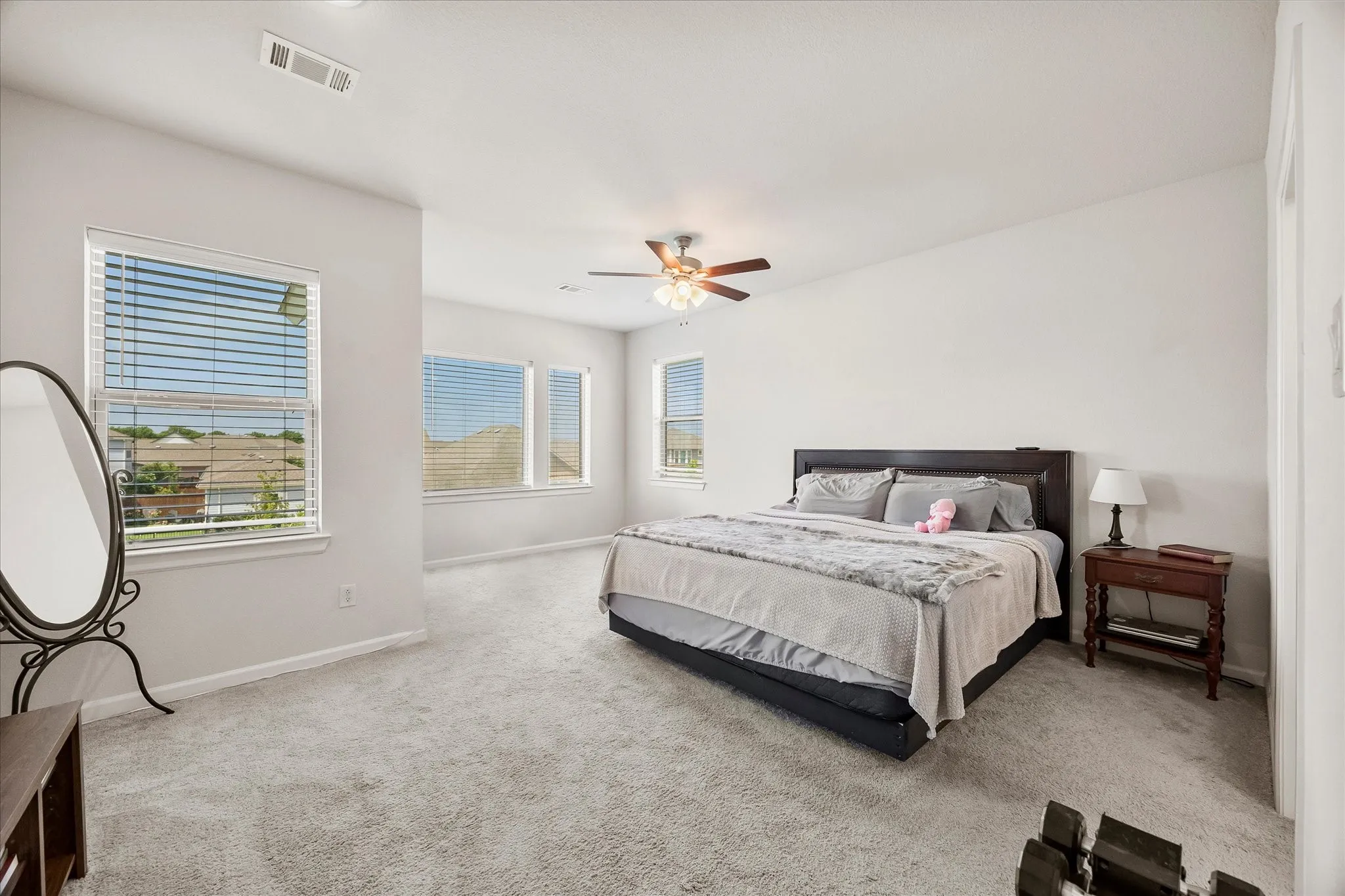 Spacious room featuring light-colored carpeting and multiple windows with horizontal blinds