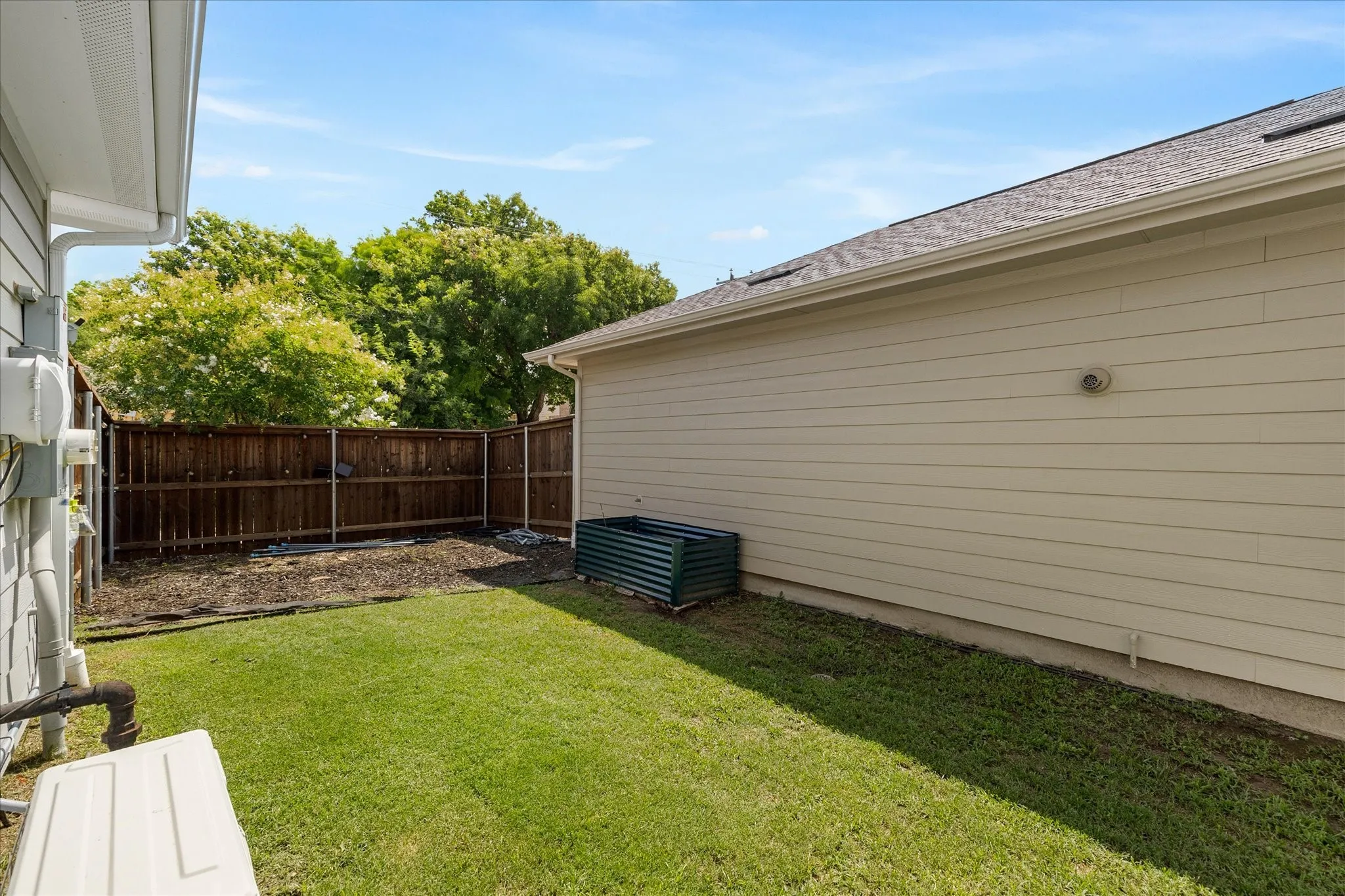 Fenced backyard with manicured lawn and a privacy fence, showcasing exterior siding and a pitched roofline