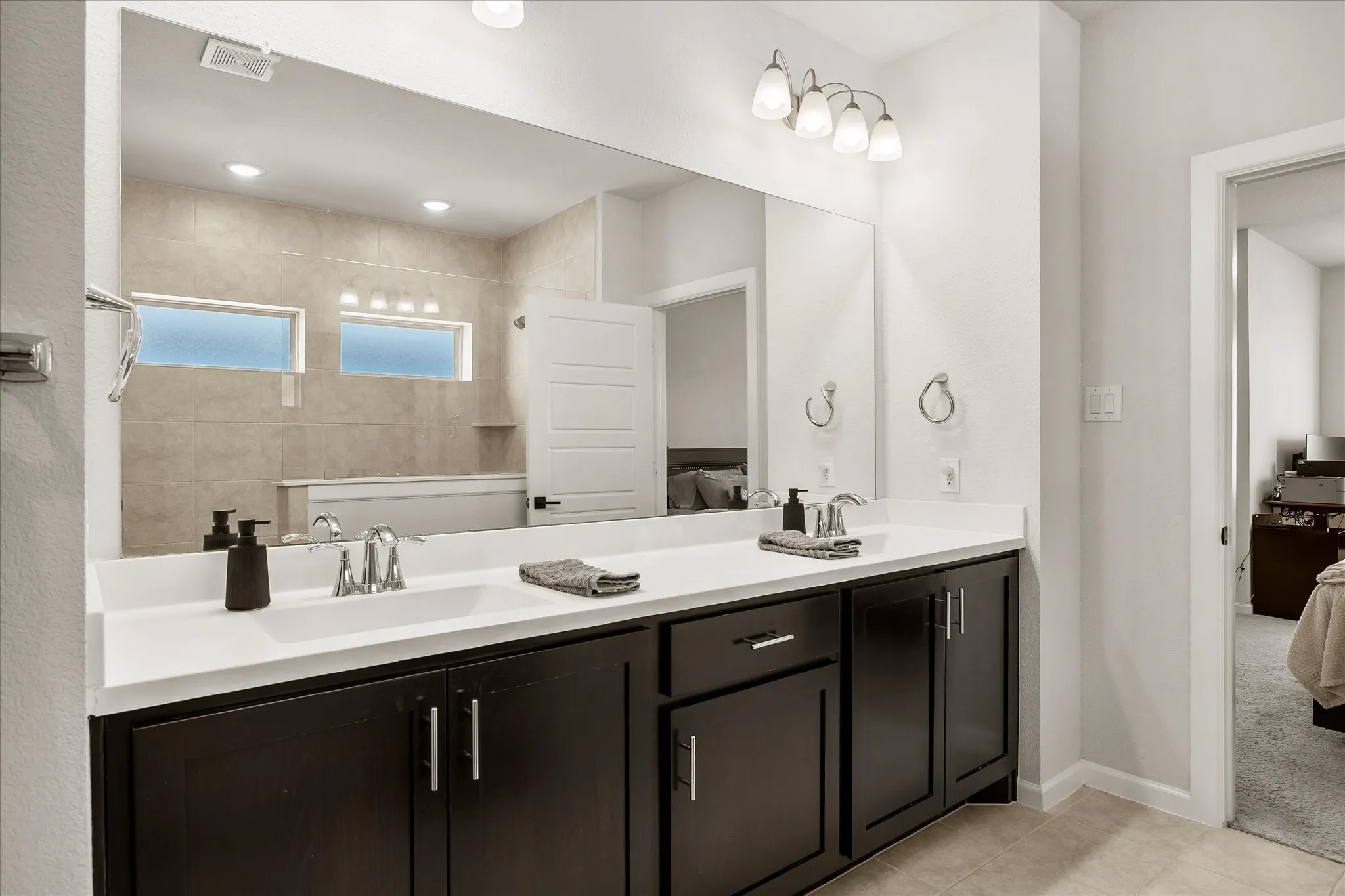 Dual basin vanity with a solid surface countertop, dark wood-finish cabinetry, and chrome fixtures