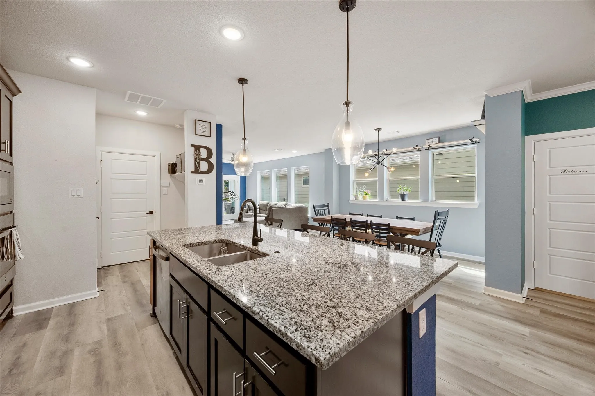 Kitchen island featuring a granite countertop, undermount stainless steel sink, and matte black faucet