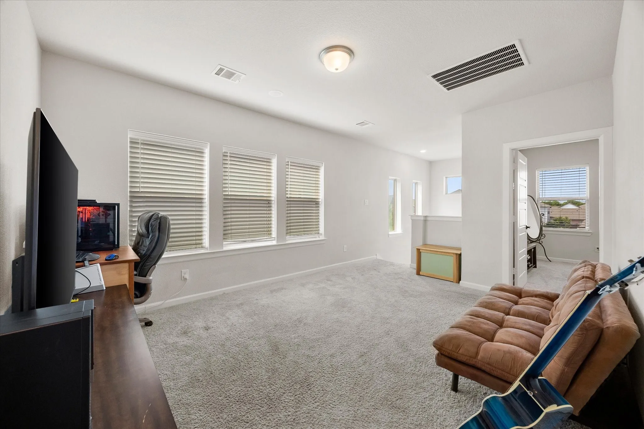 Spacious carpeted room featuring multiple windows with blinds, light gray wall paint, and a ceiling-mounted light fixture