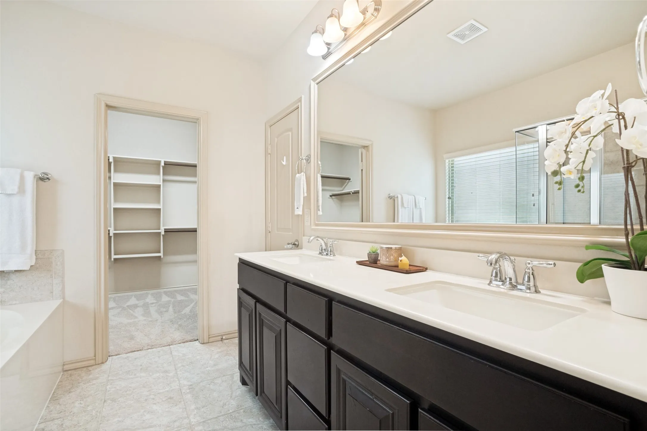 Bathroom featuring a dual vanity with dark wood cabinetry, white countertops, and chrome fixtures