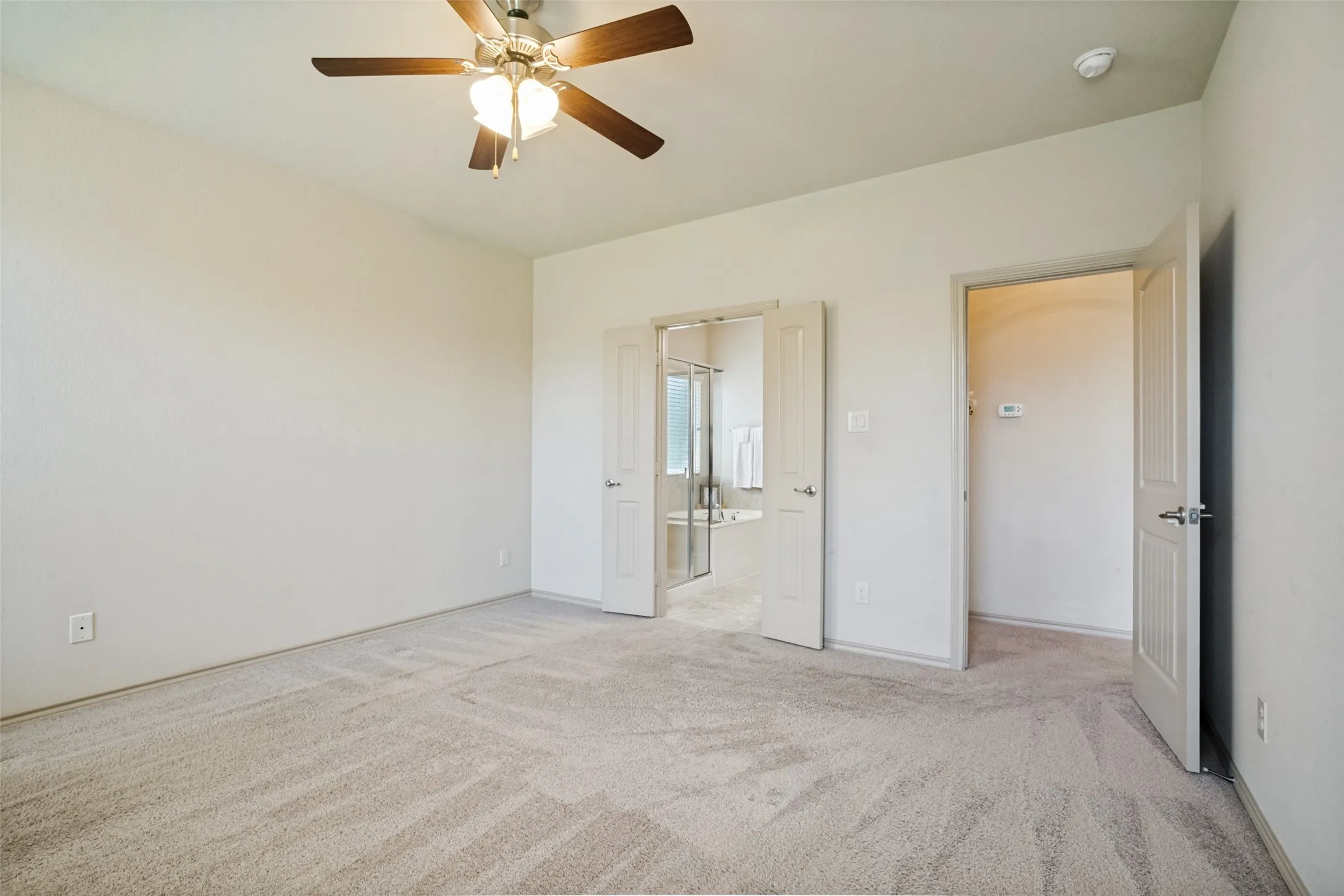 Spacious bedroom featuring light-toned carpeting, a ceiling fan with integrated lighting, and neutral wall tones