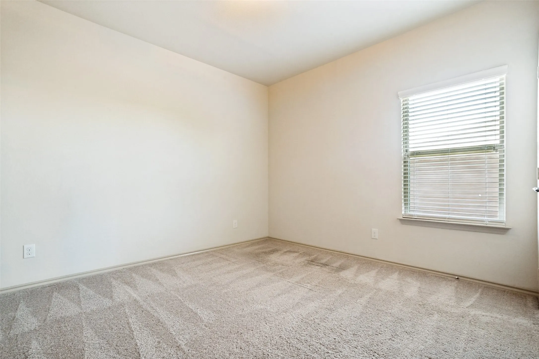 Neutral-toned room featuring a single window with horizontal blinds