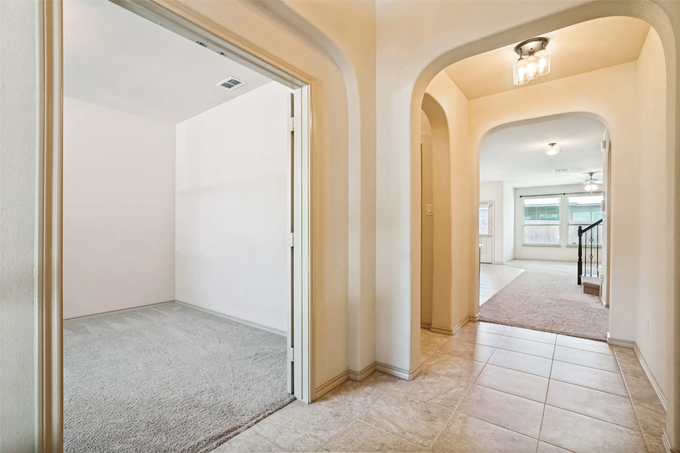 Arched doorways opening to an office off the entryway and tiled hallway