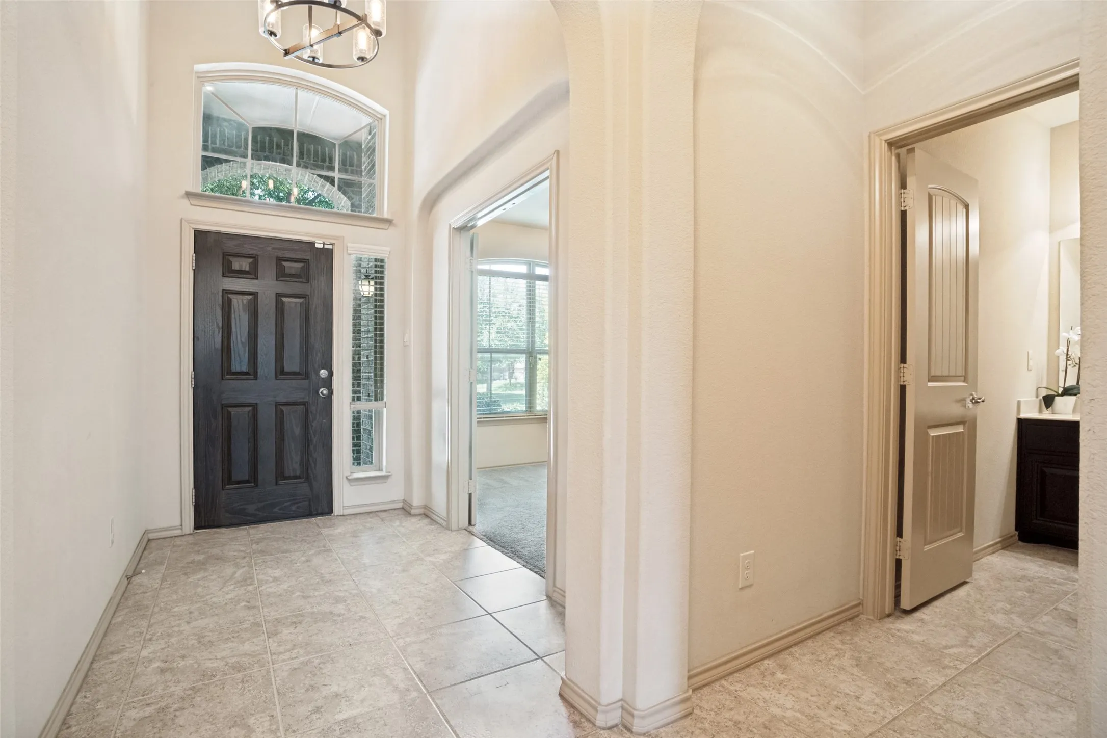 Entryway featuring a dark paneled door, transom window, and tiled flooring