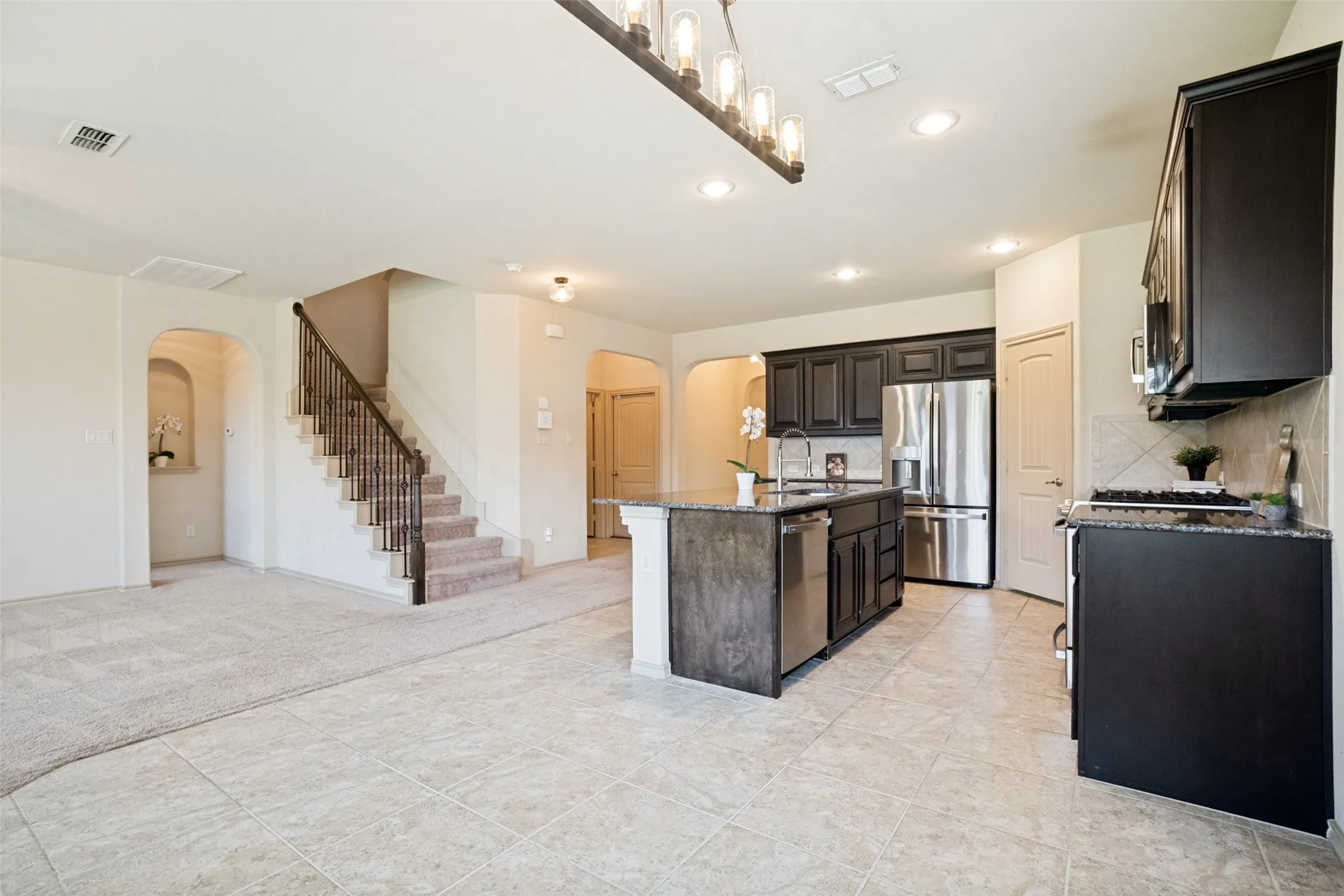 Open-concept living area with tile flooring and plush carpeting