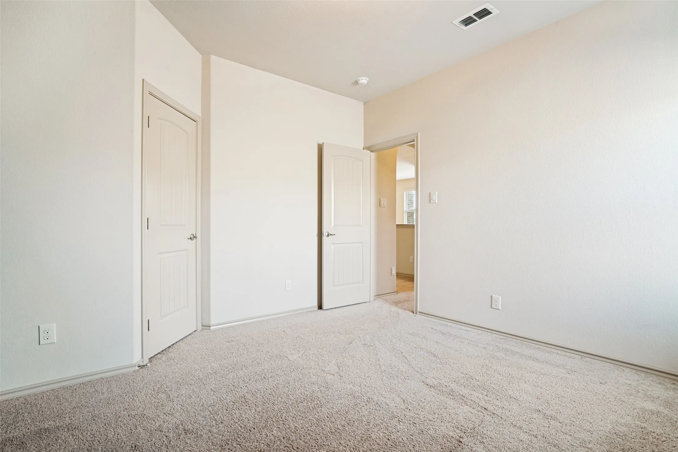 Open room featuring light beige textured carpeting and neutral wall tones