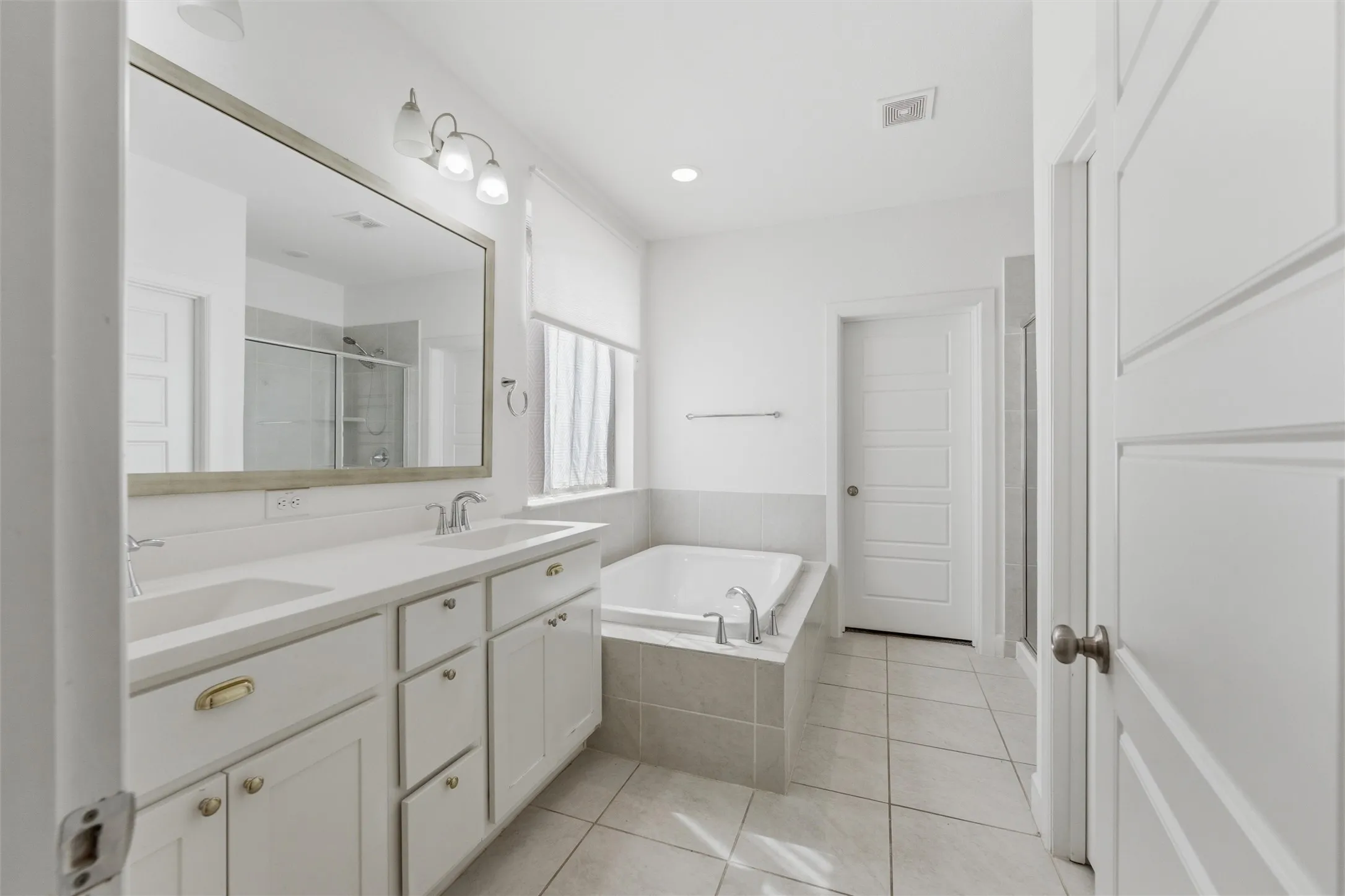 Bright bathroom with a spacious vanity featuring dual sinks and an expansive mirror