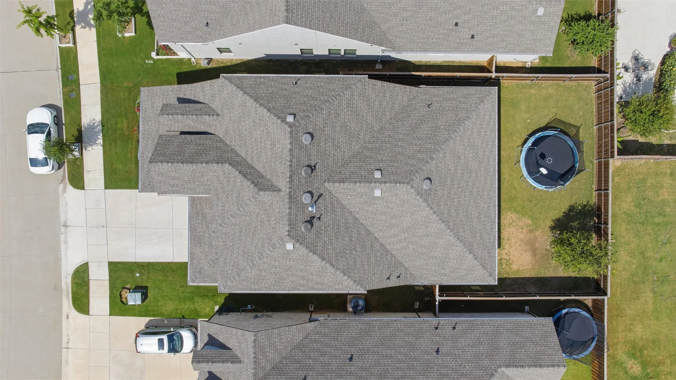 Aerial perspective showcasing the property's shingle roof, expansive backyard, and paved driveway