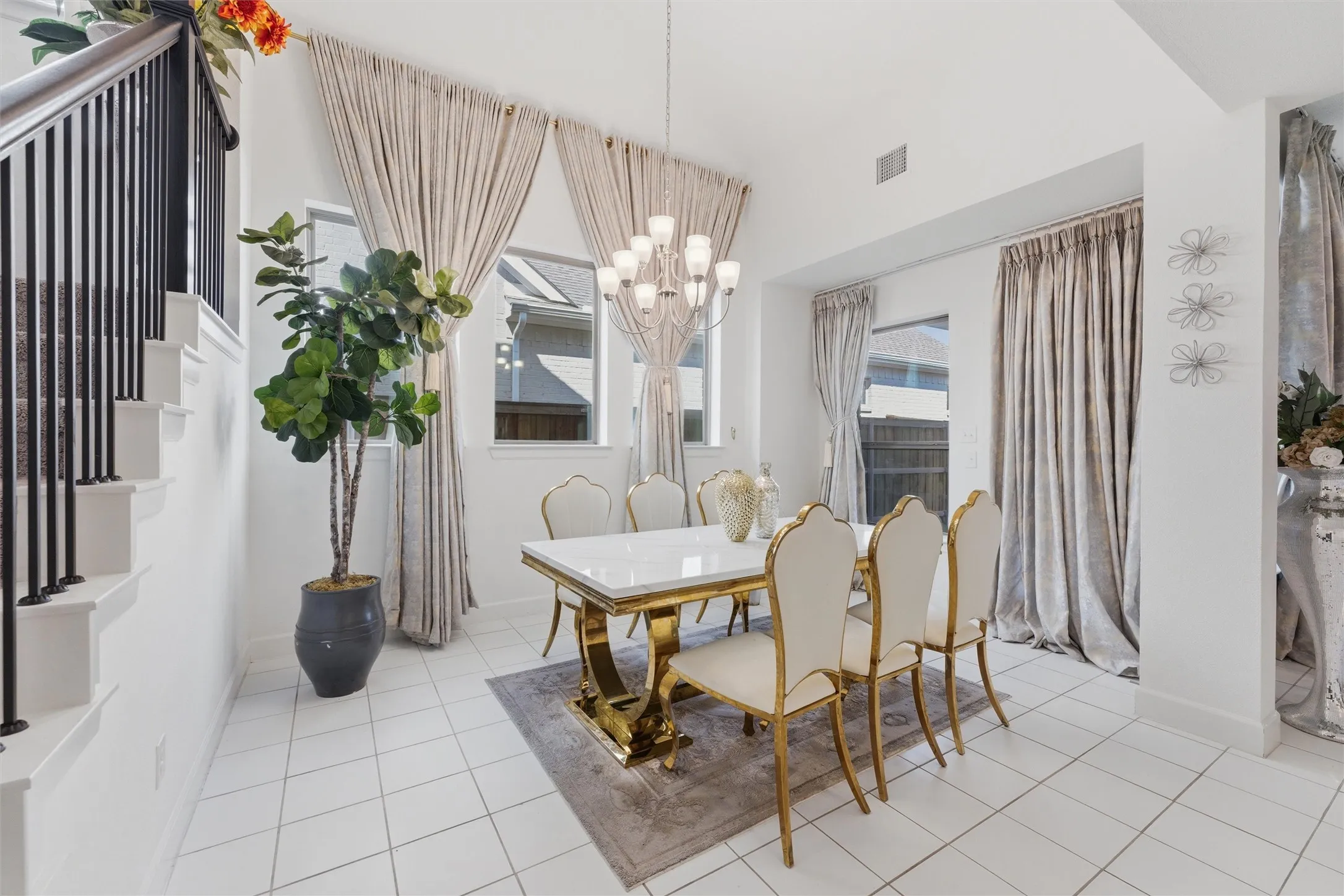 Dining area featuring a contemporary multi-light chandelier, high ceilings, multiple windows with drapes, and tiled flooring