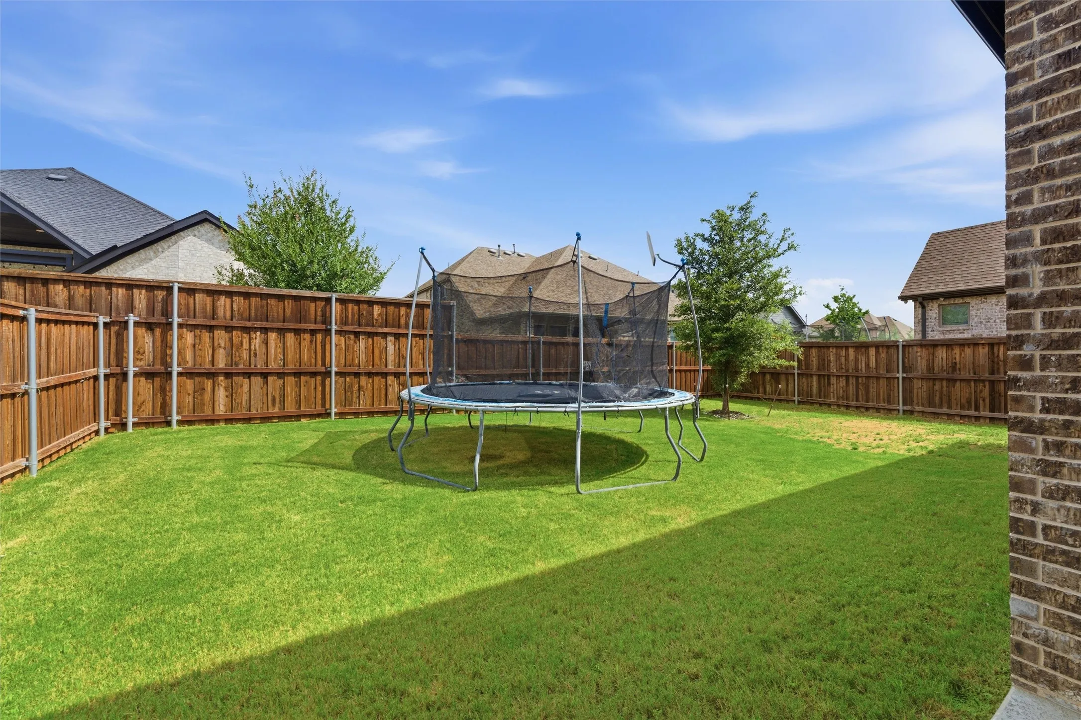 Spacious backyard featuring a lush green lawn, full wood privacy fencing, and a mature tree