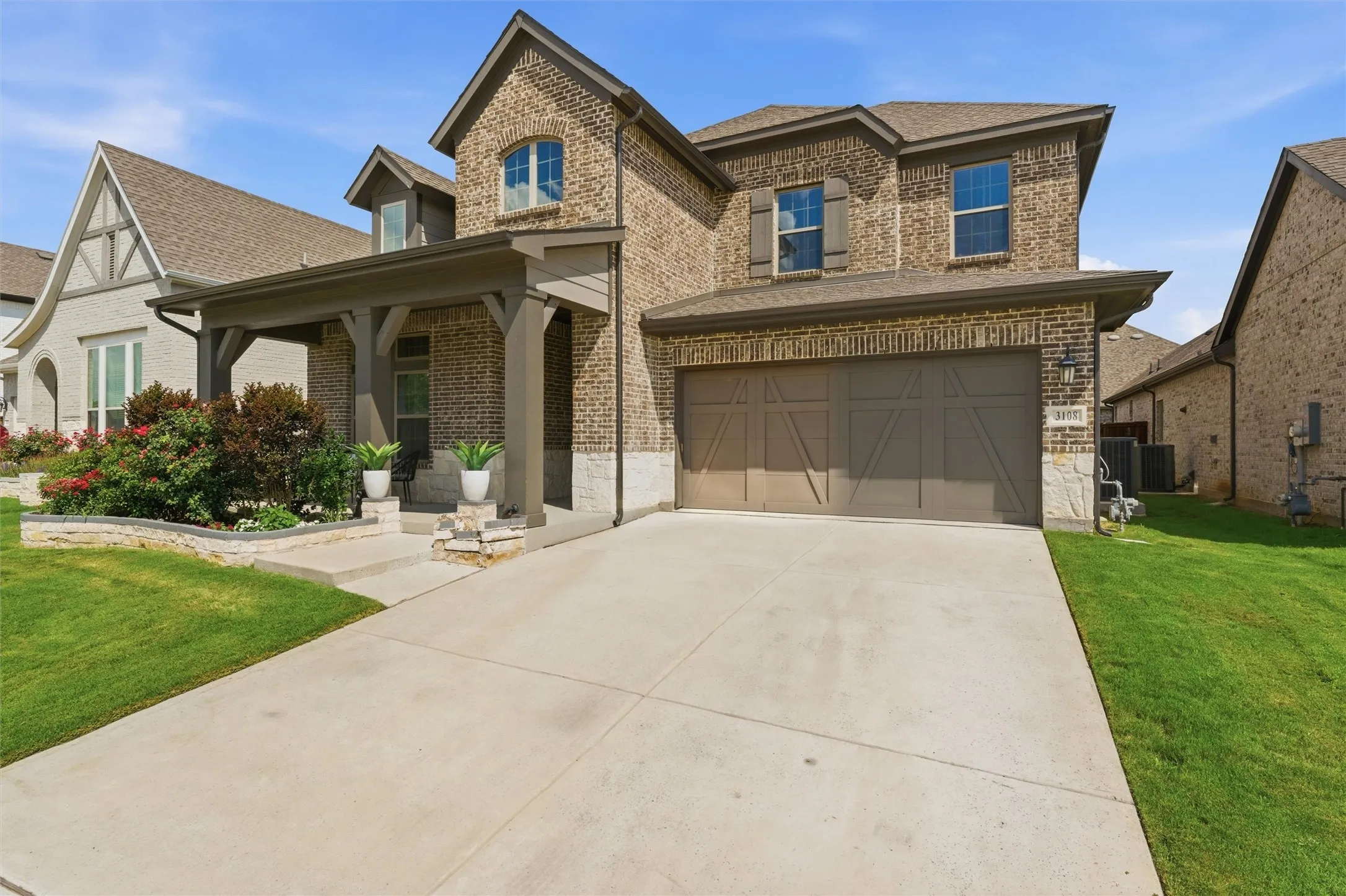 Brick exterior with stone accents, covered front porch, and a two-car garage