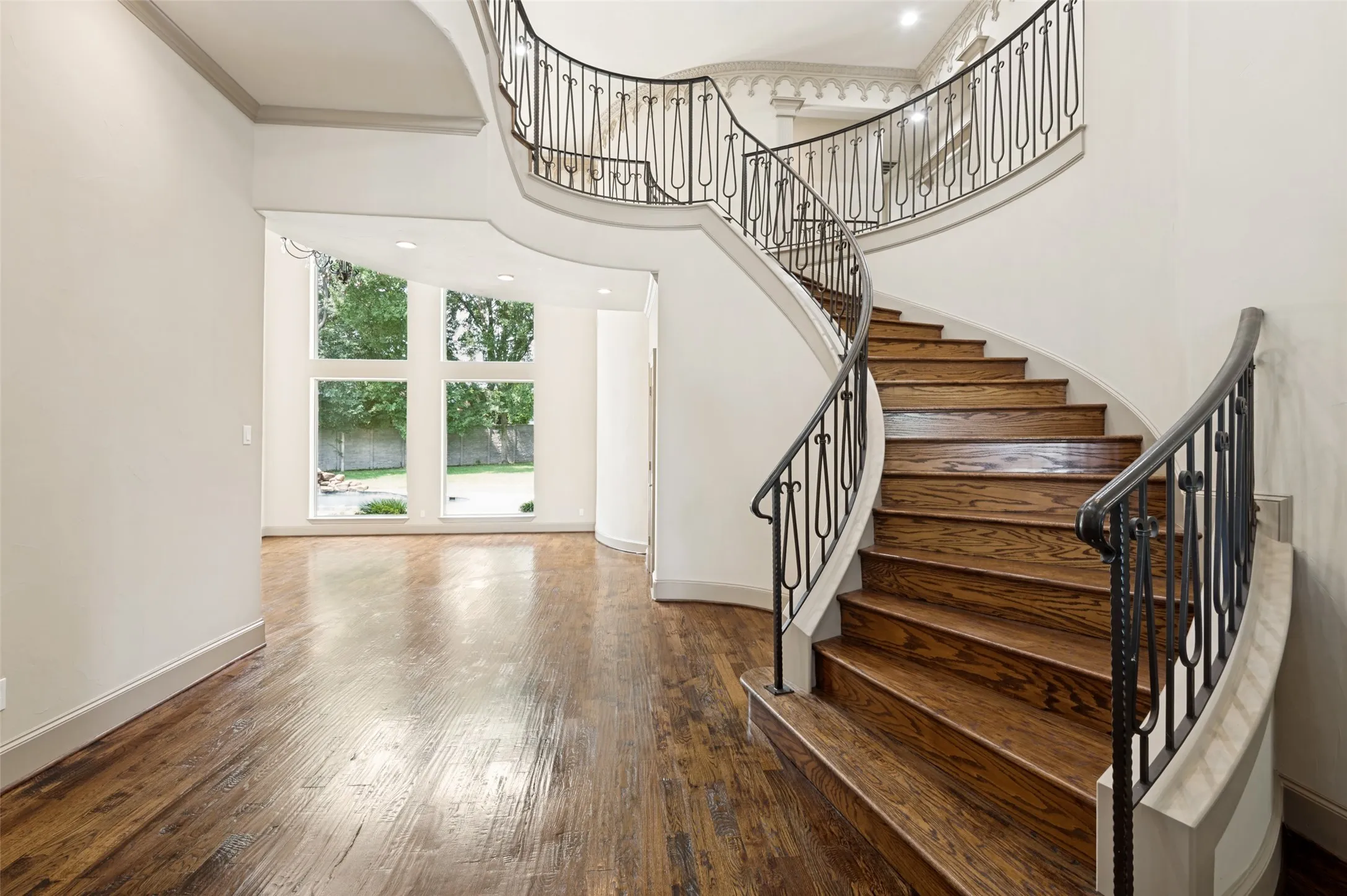 Spacious entry featuring hand scraped hardwood floors and spiraling showcase stairway accented with custom designed iron railings.