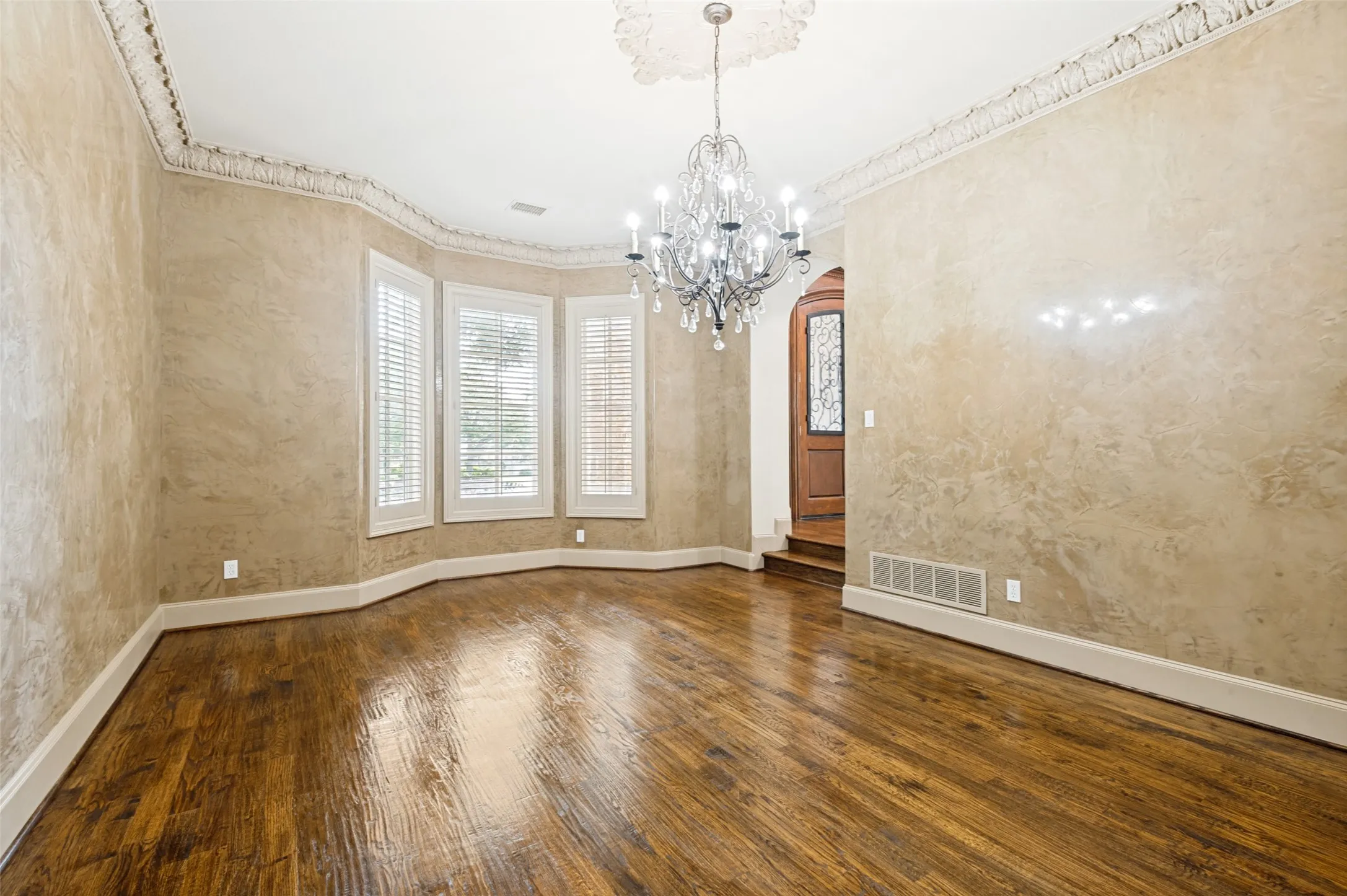 Formal dining room features rich Venetian-plaster walls, classic plantation shutters, and elegant decorative lighting for a refined setting.