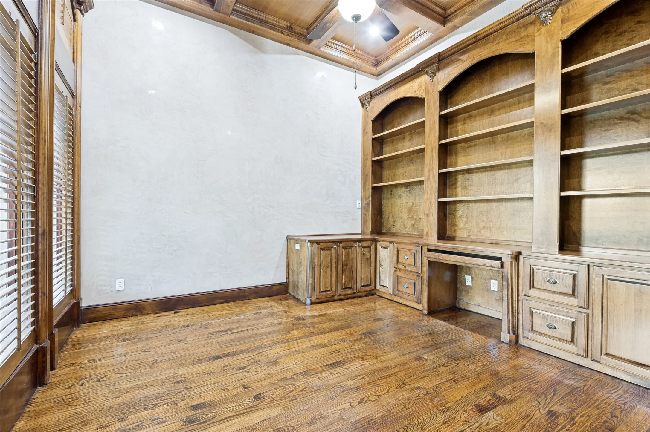 Rich stained oak built-in credenza, plantation shutters, and hardwood flooring add warmth, character, and appeal for home office or study.