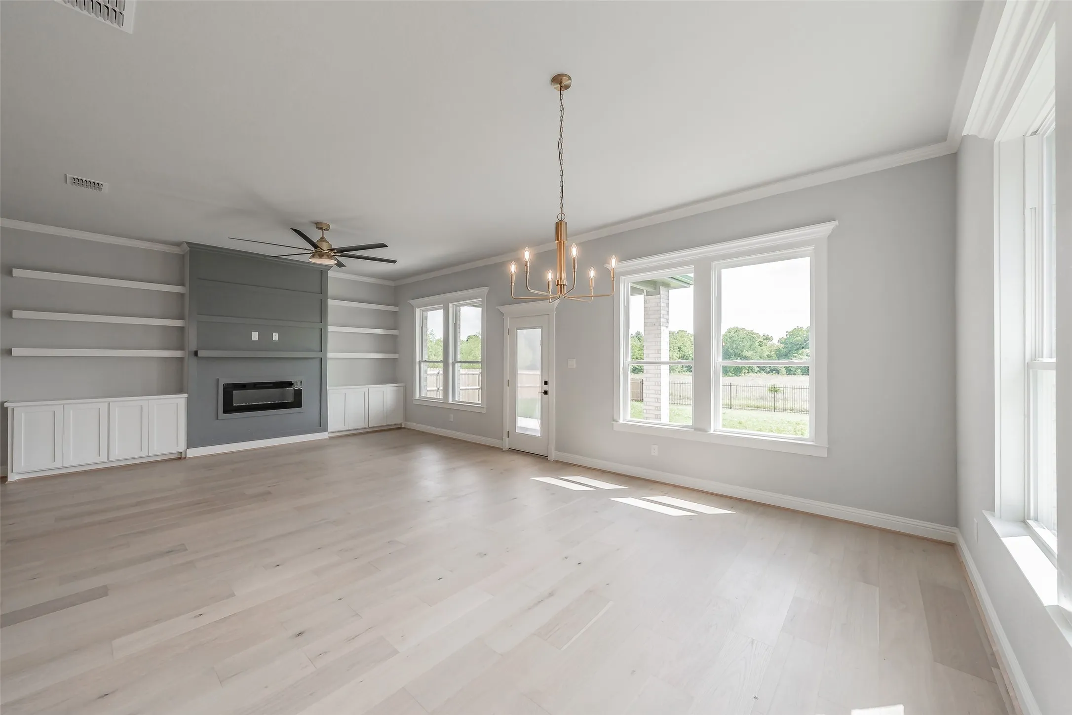 Huge living room features an electric fireplace & built in cabinets & shelving