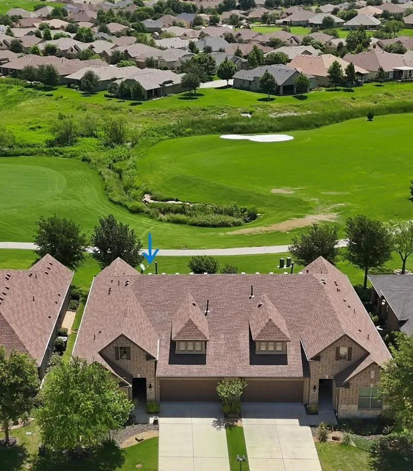 Aerial perspective showcasing a residential property with a multi-gabled roofline, front-facing garages, and a brick exterior