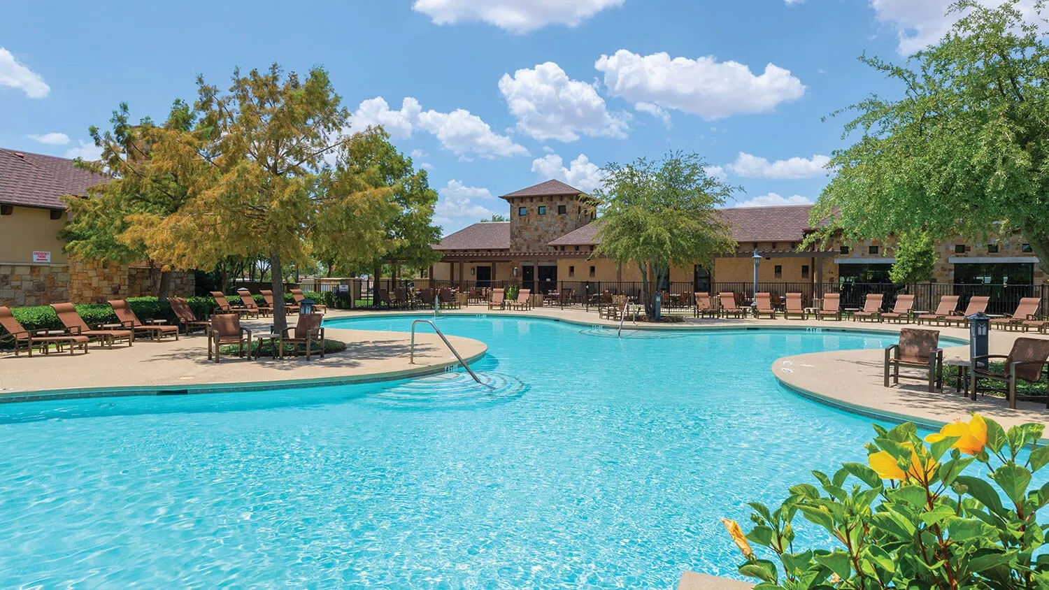 Expansive resort-style swimming pool featuring a curved design and integrated sun ledges