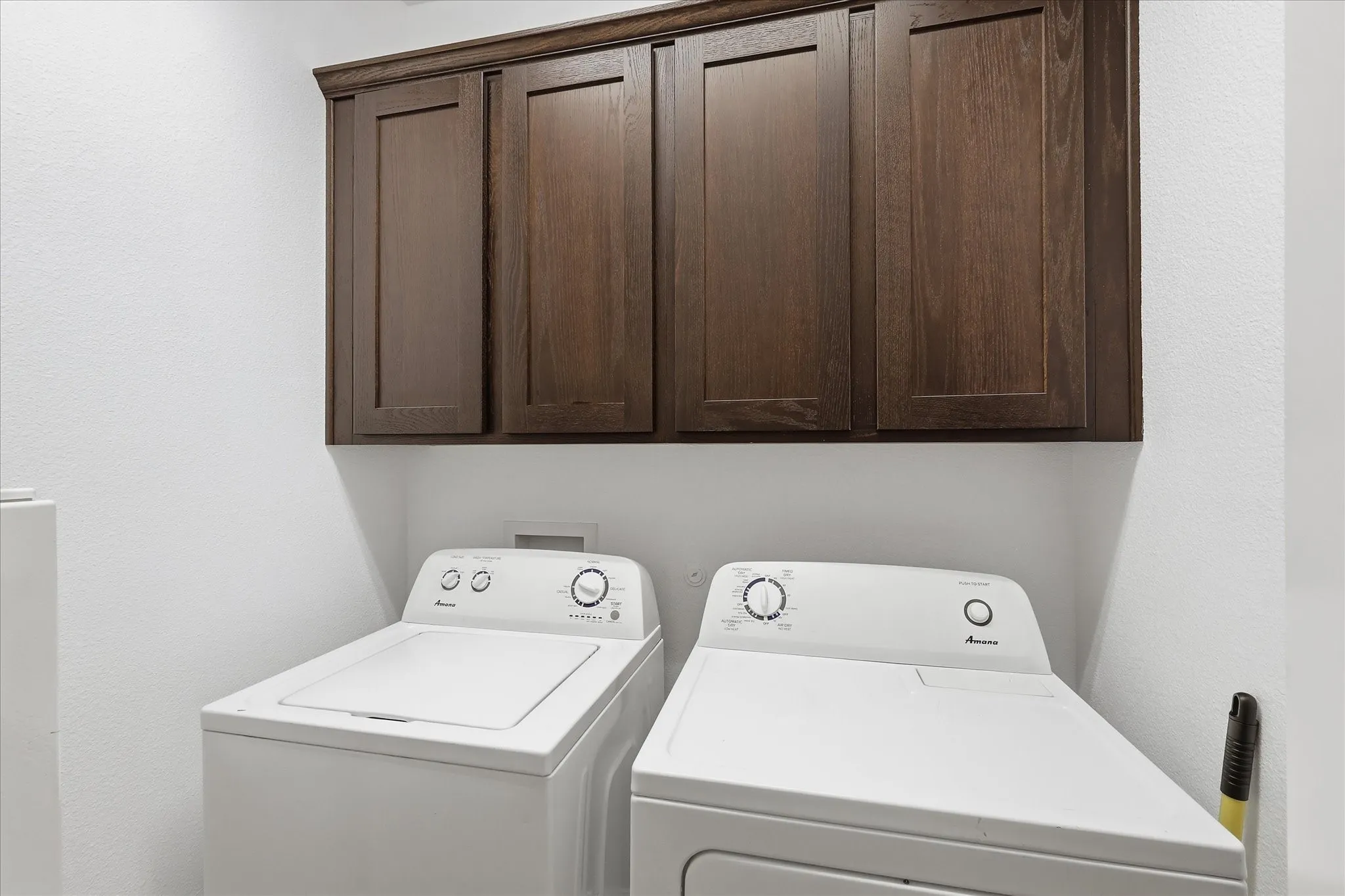 Dedicated laundry area featuring white walls and built-in dark wood-finish cabinetry
