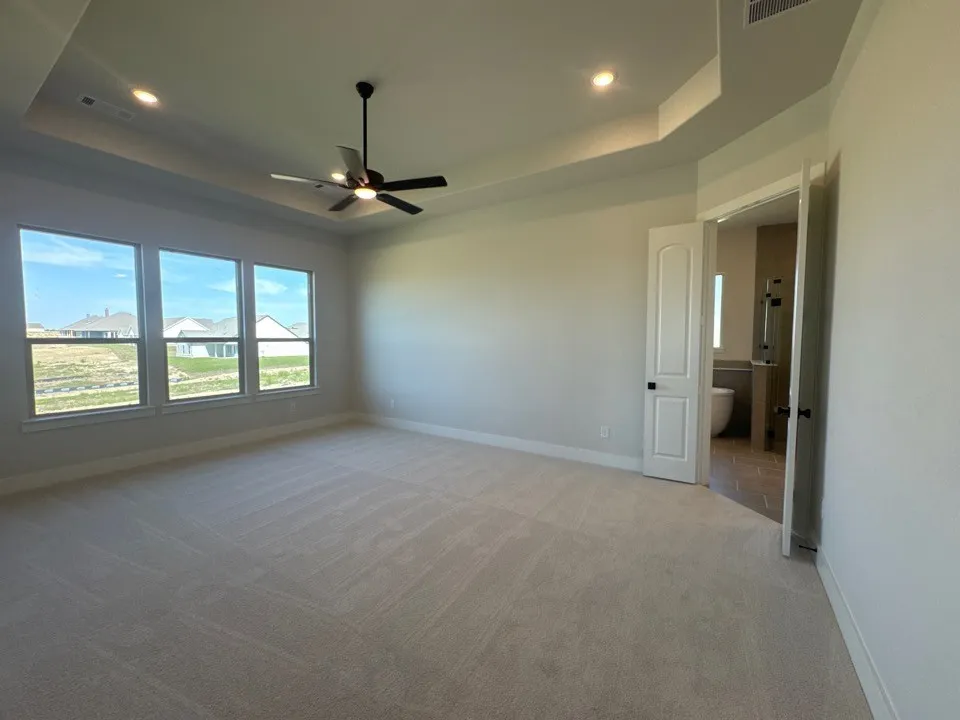 Kitchen island with pendant lighting, white cabinetry, integrated stainless steel appliances, and wood-finish flooring throughout