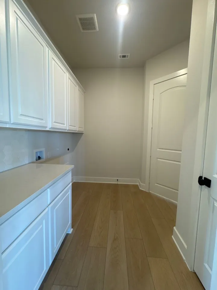 White shaker-style cabinetry, light wood-finish flooring, recessed lighting, and a white countertop