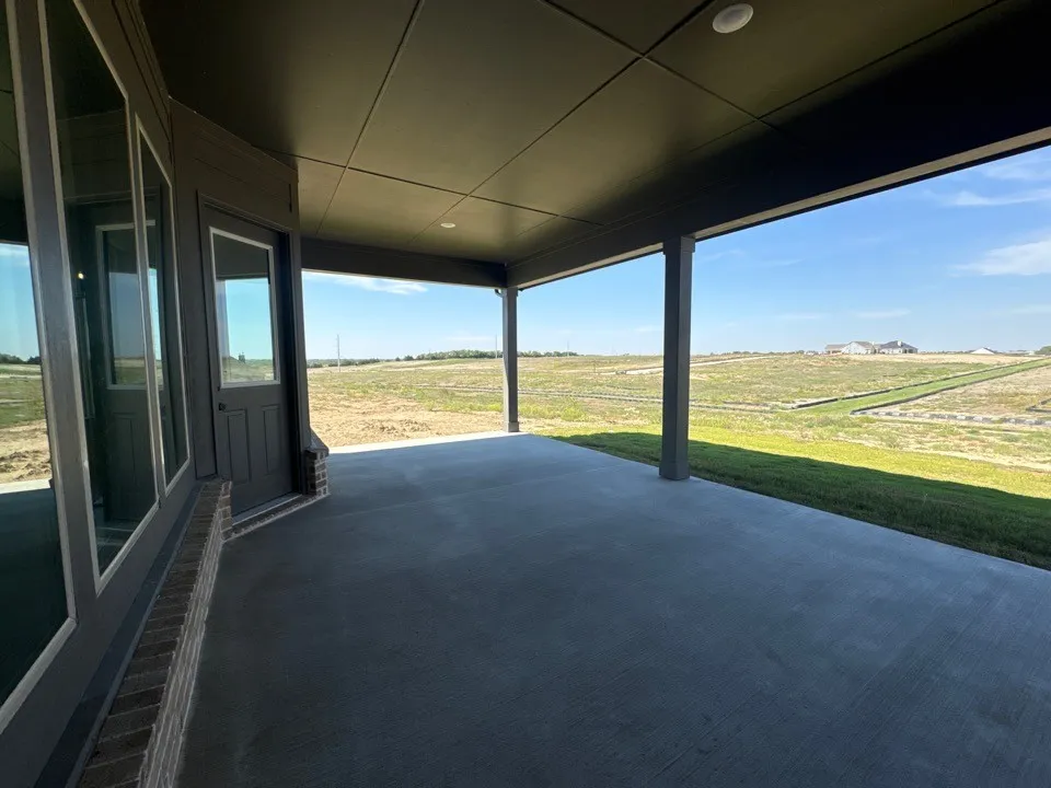 Expansive covered patio with concrete flooring, recessed lighting, and brick detailing
