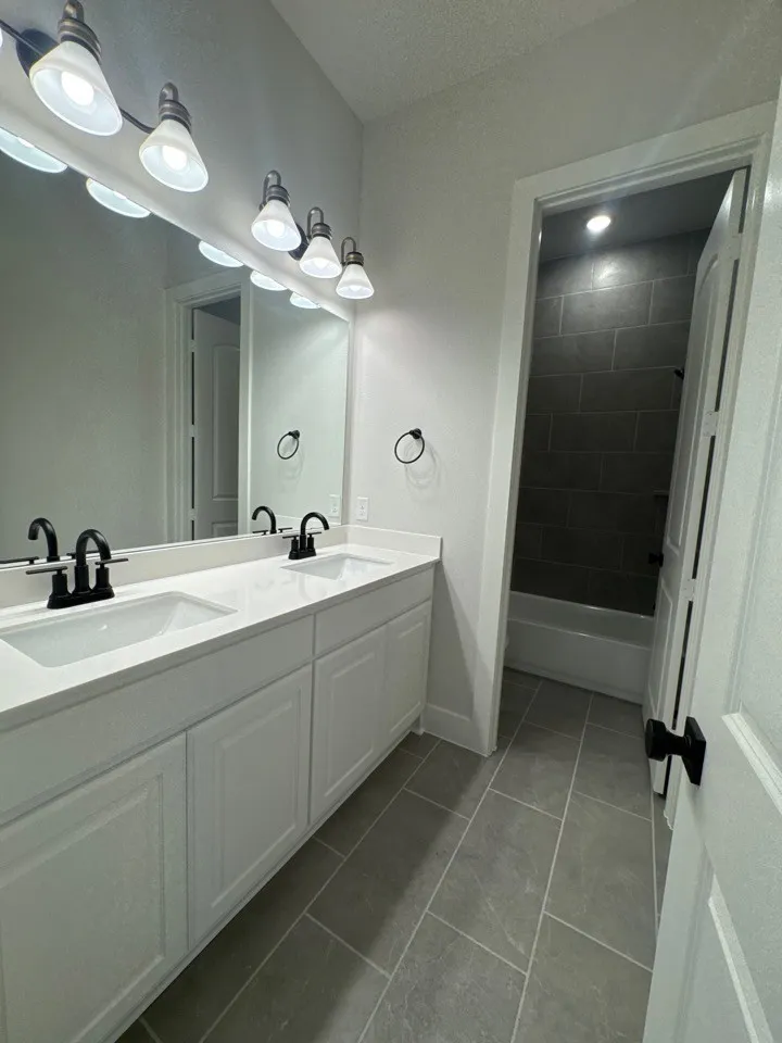 Dual vanity with white cabinetry, integrated sinks, white countertops, and black hardware