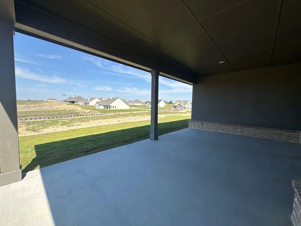 Covered concrete patio with recessed lighting and a brick accent wall