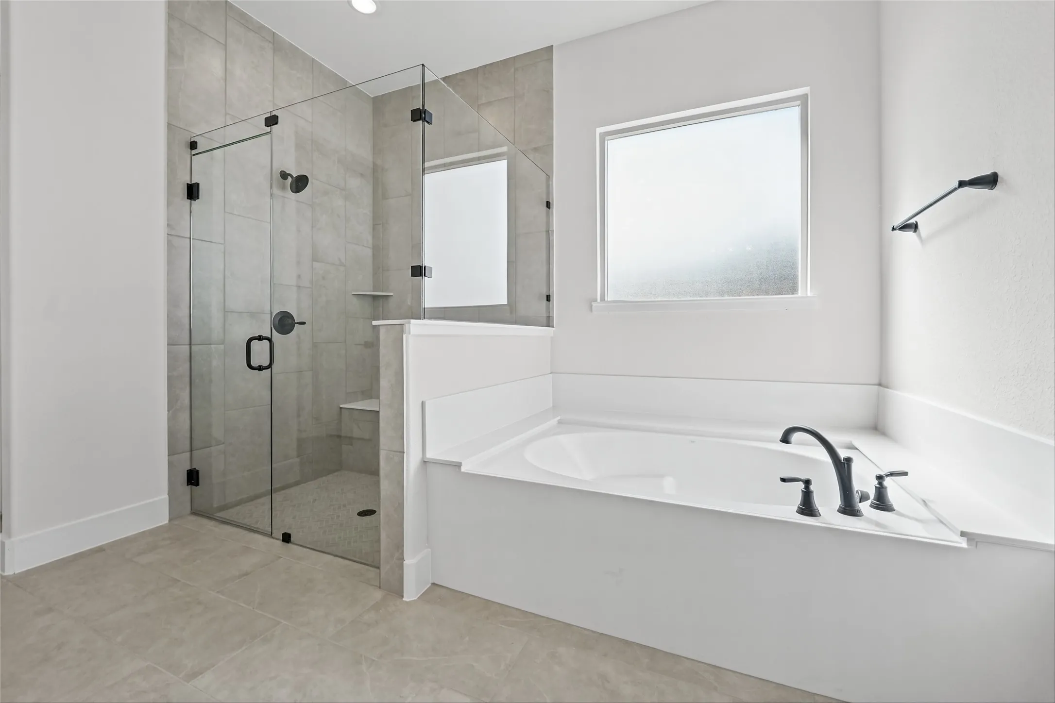 Spacious bathroom featuring a built-in soaking tub with matte black fixtures, a walk-in shower with a glass enclosure, a tiled shower surround, and a built-in shower bench