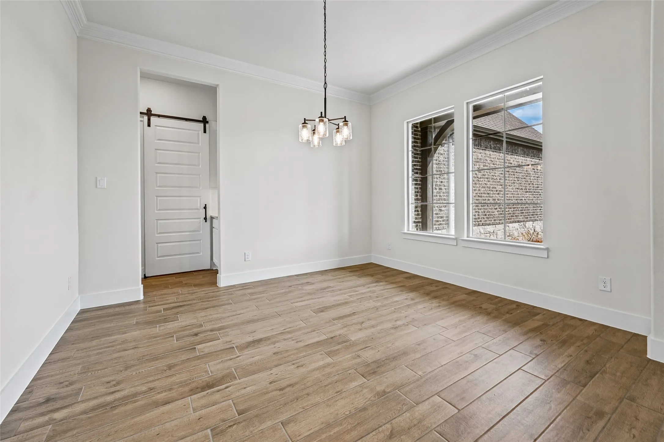 Wood-finish flooring throughout, complemented by a modern chandelier and two large windows