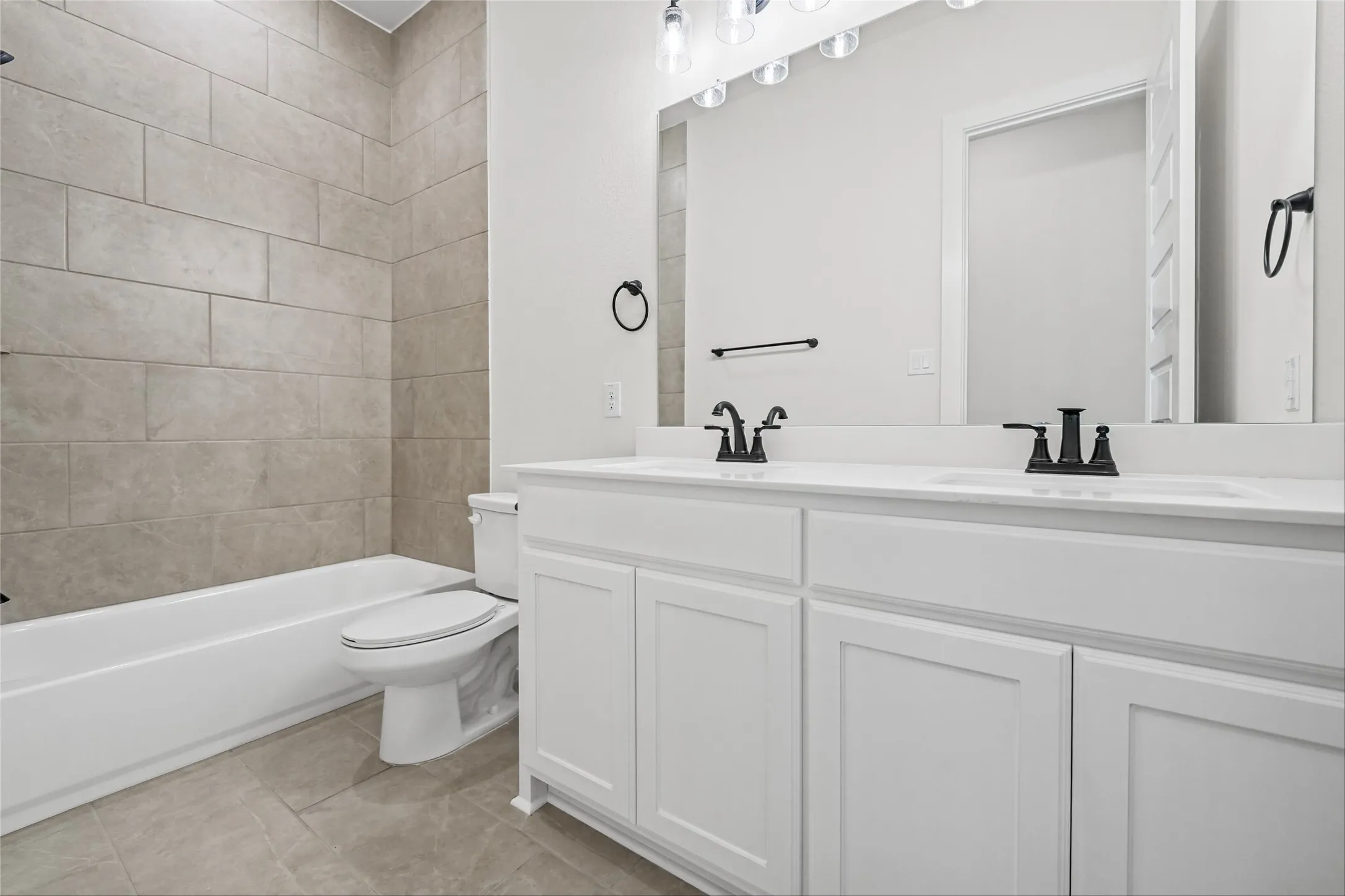 Dual vanity with white cabinetry, matte black hardware, and an expansive mirror