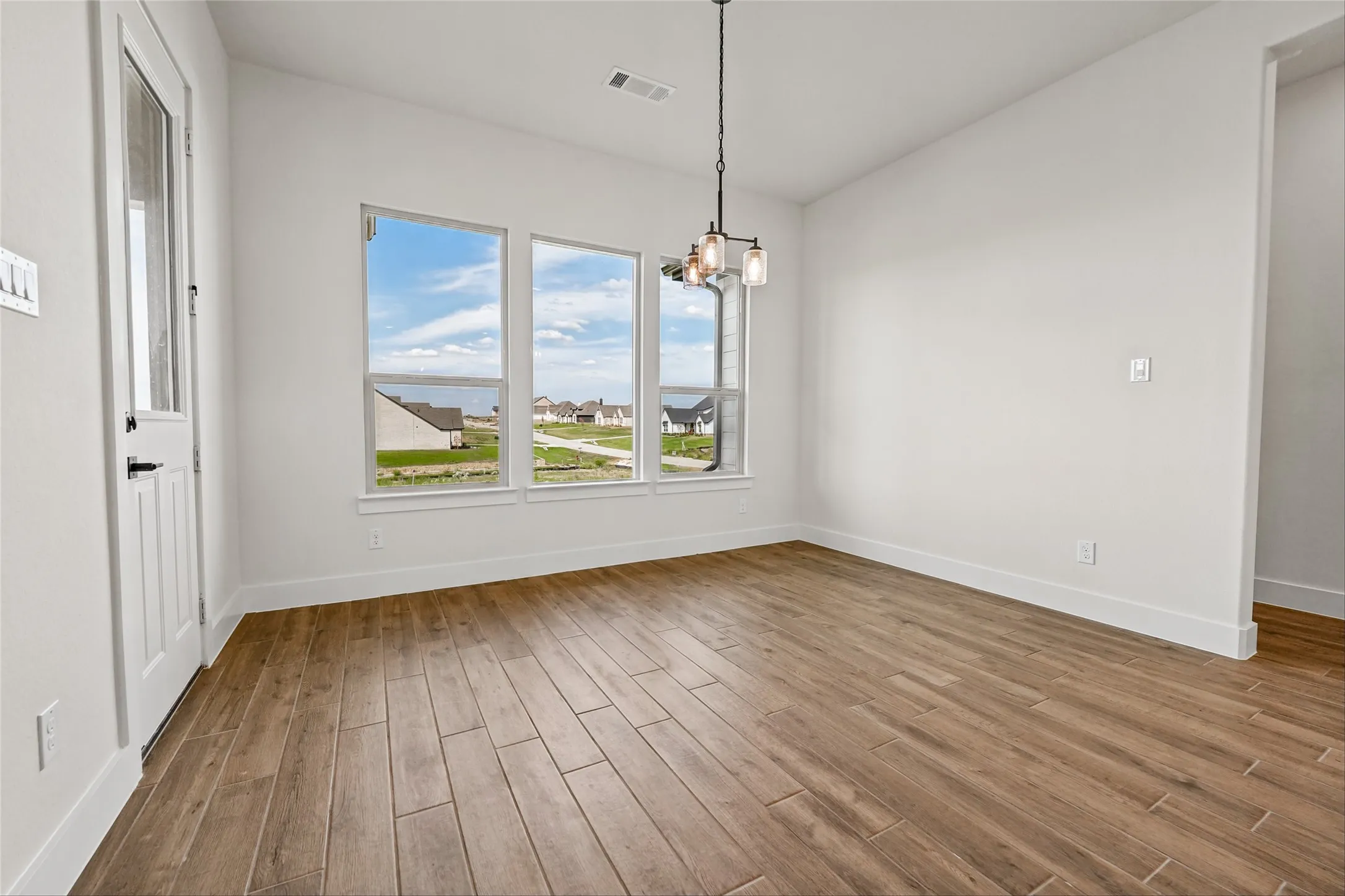 Wood-finish flooring, white trim, and multiple windows providing natural illumination