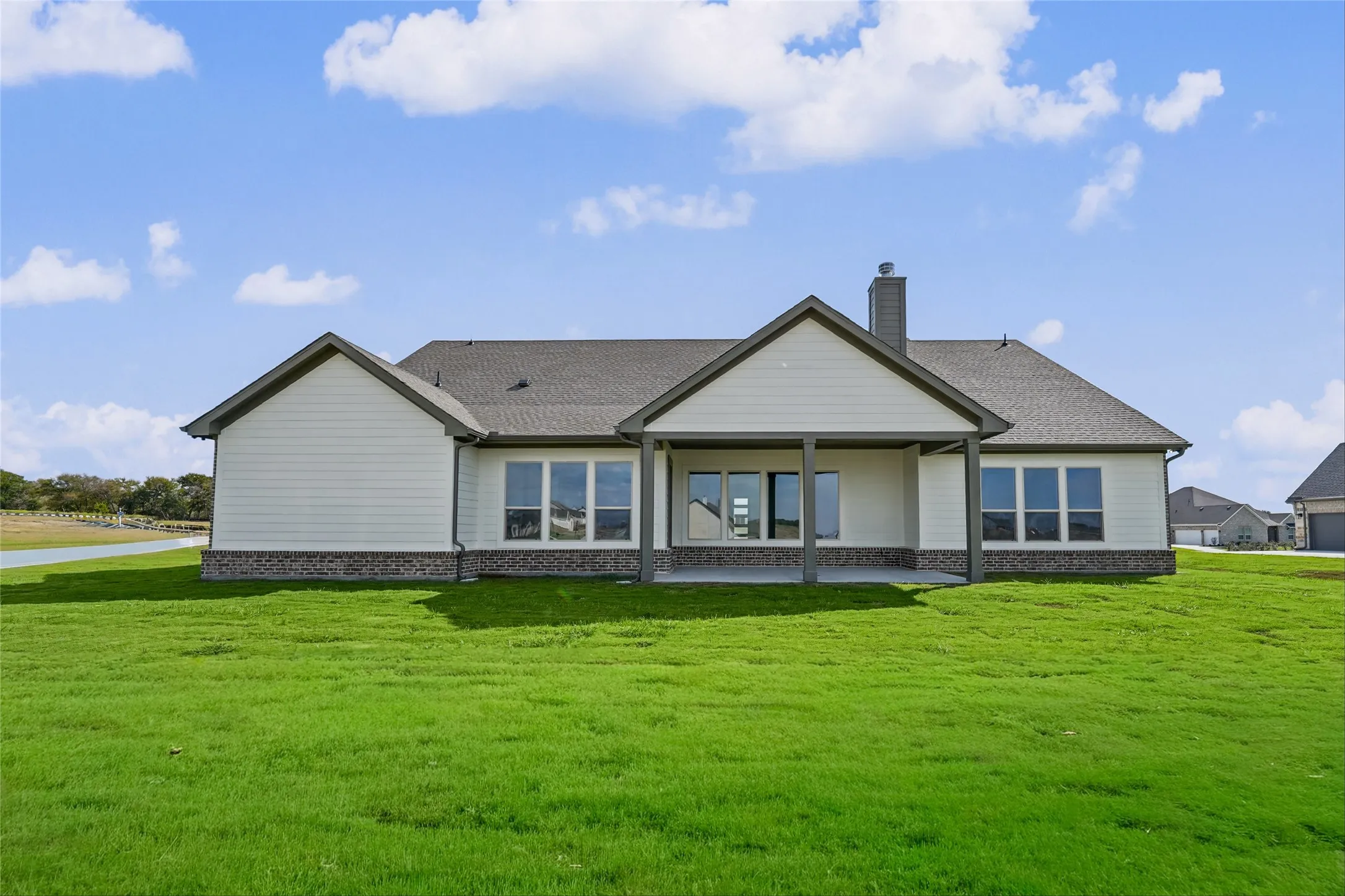 Single-story residence featuring light-colored siding, a covered patio, and a shingled roof