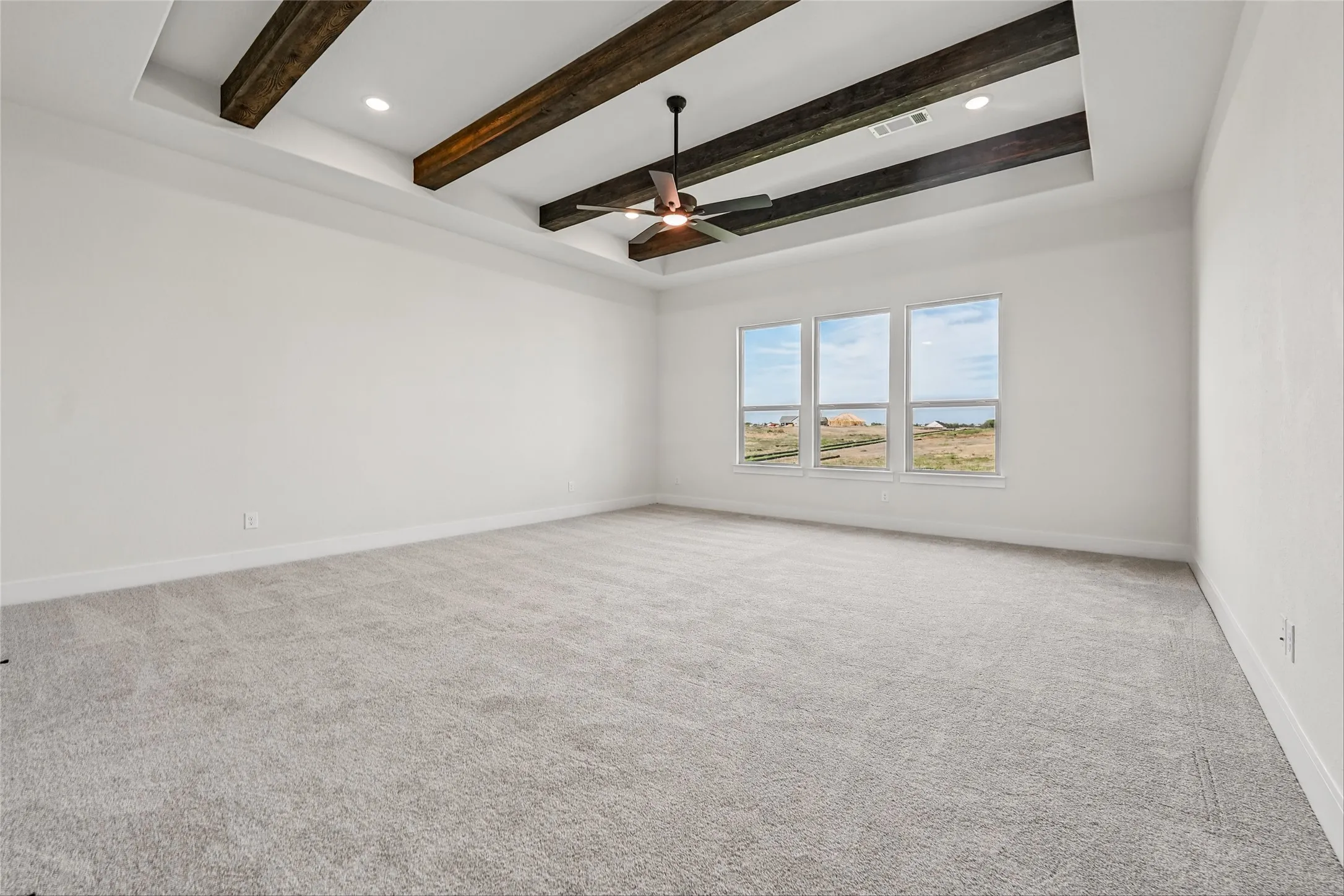 Tray ceiling with wood-finish beams, recessed lighting, and a ceiling fan