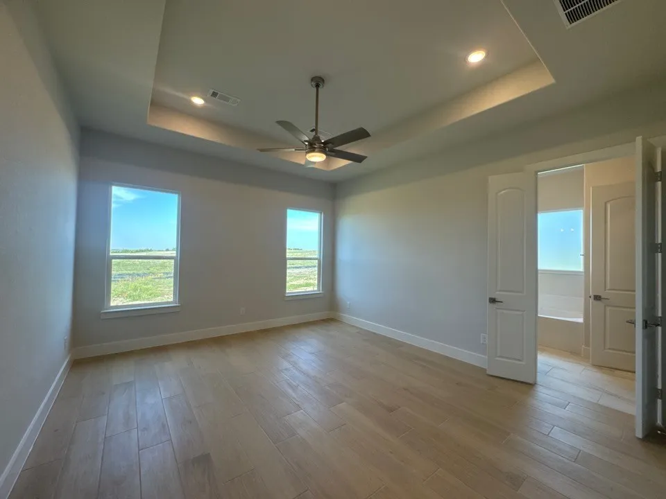Recessed lighting, ceiling fan, wood-finish flooring, two windows, and tray ceiling
