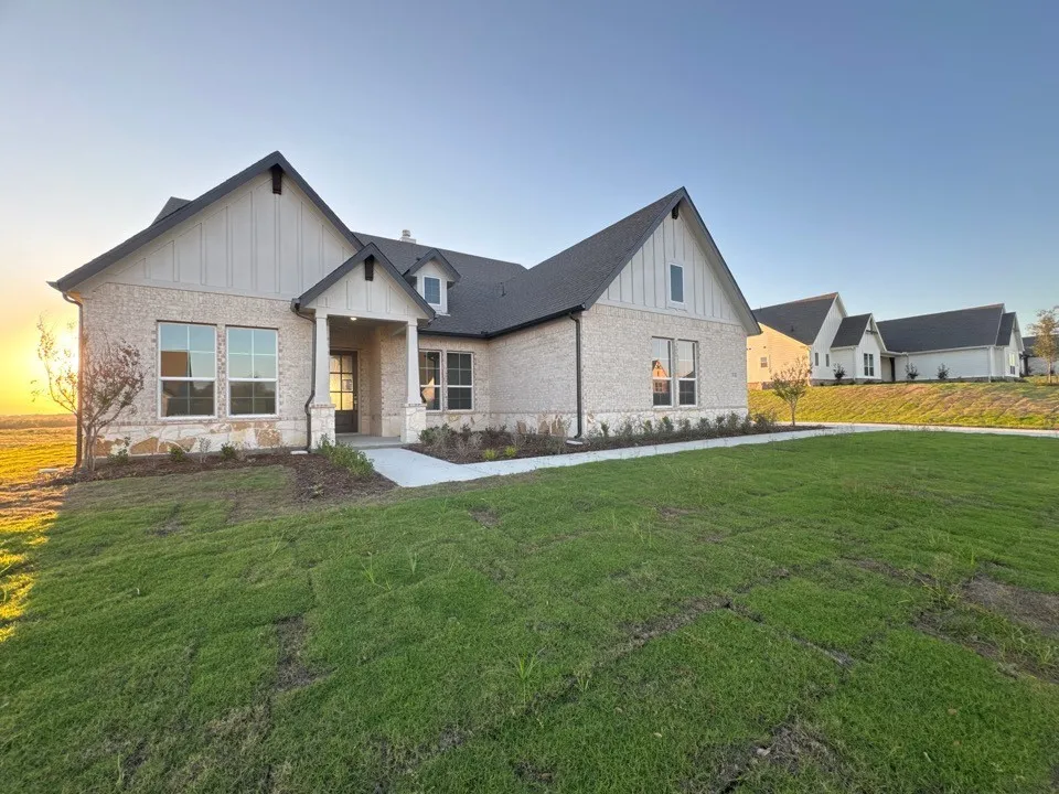 Exterior featuring a light brick facade, stone accents, dark gabled roof, and a covered entry