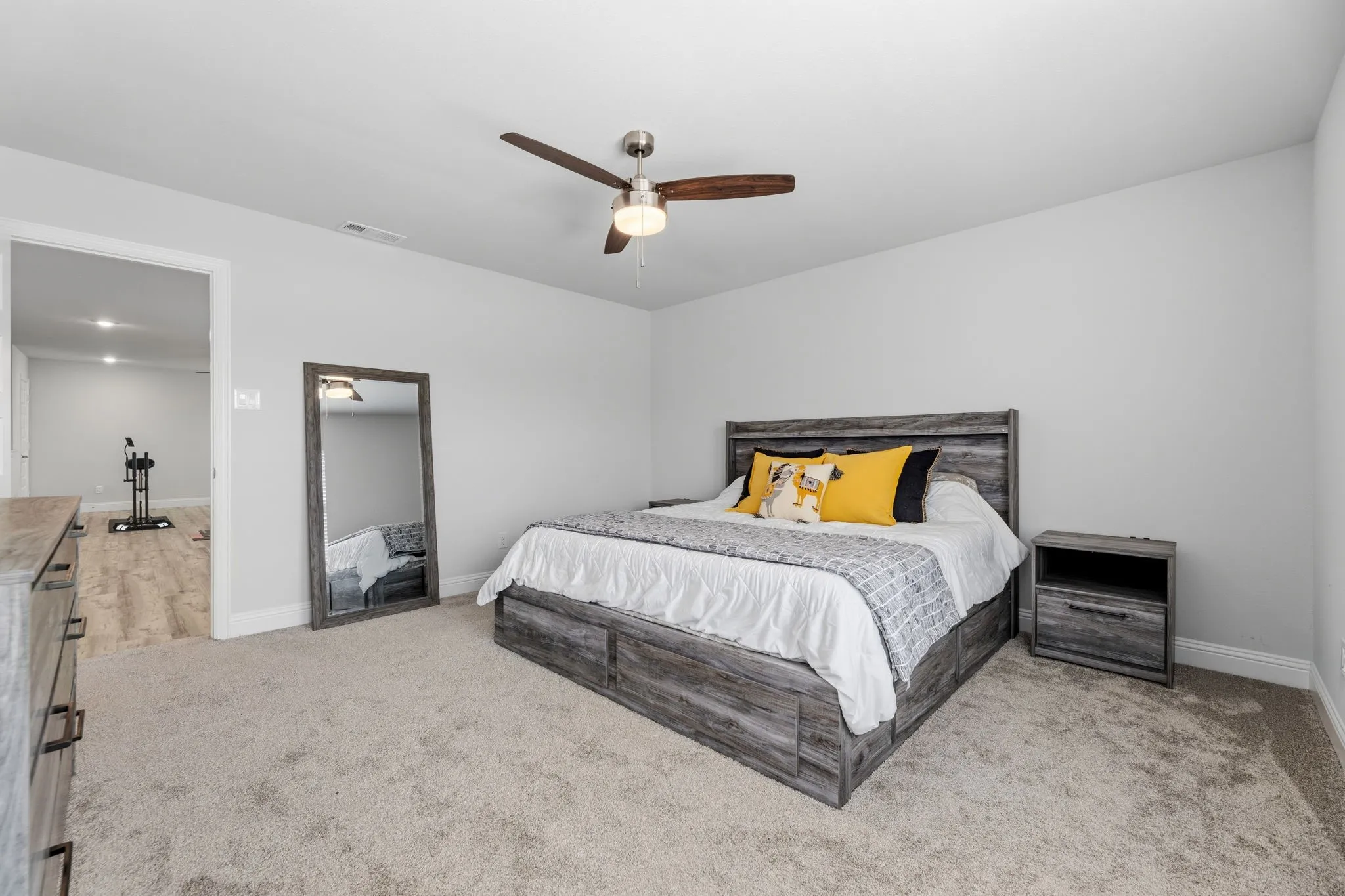 Carpeted room featuring a ceiling fan with integrated lighting, neutral wall tones, and white trim