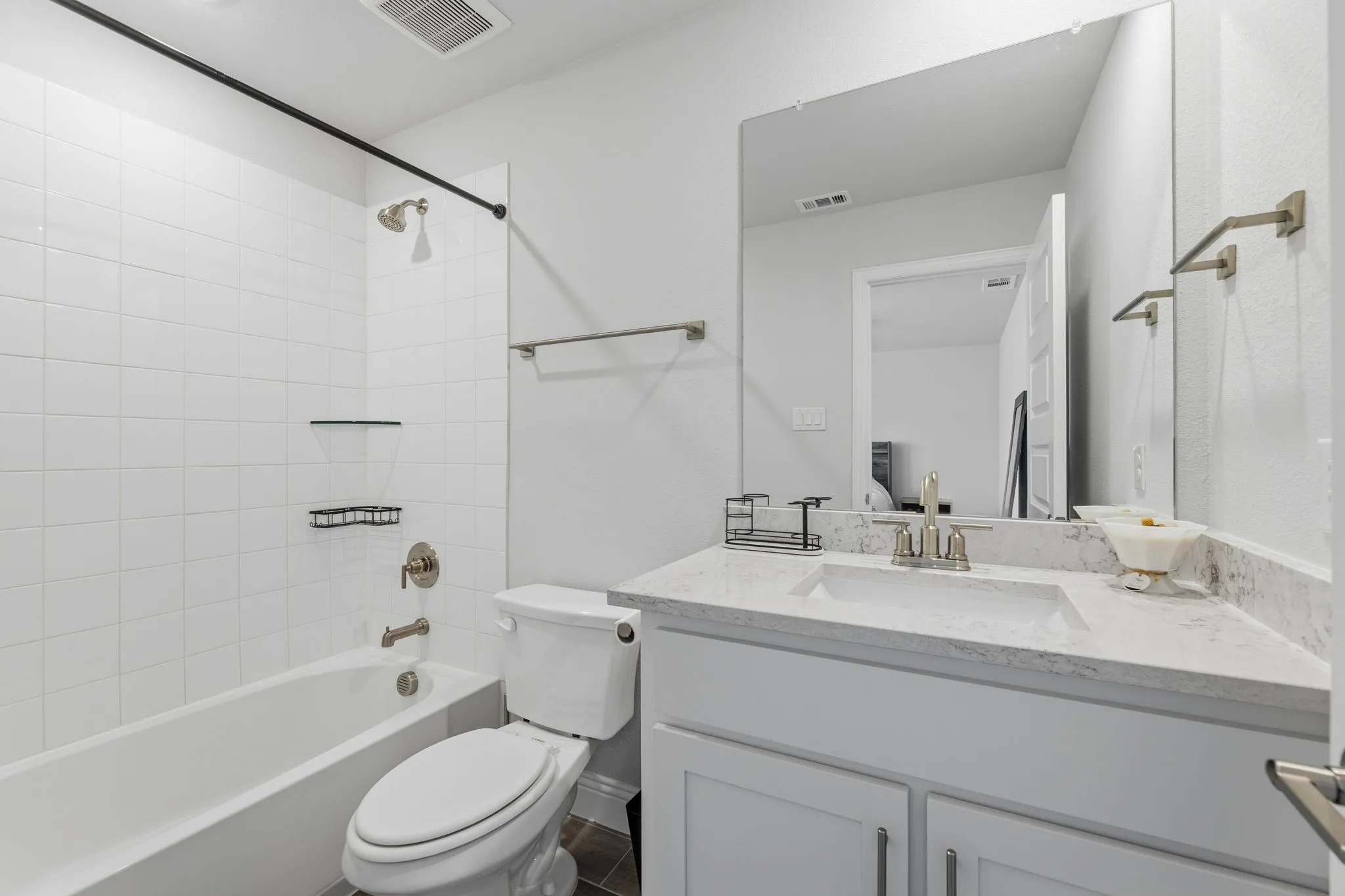 Bathroom featuring a tub/shower combination with white subway tile surround, a built-in white vanity with a light-toned countertop, and a large wall-mounted mirror