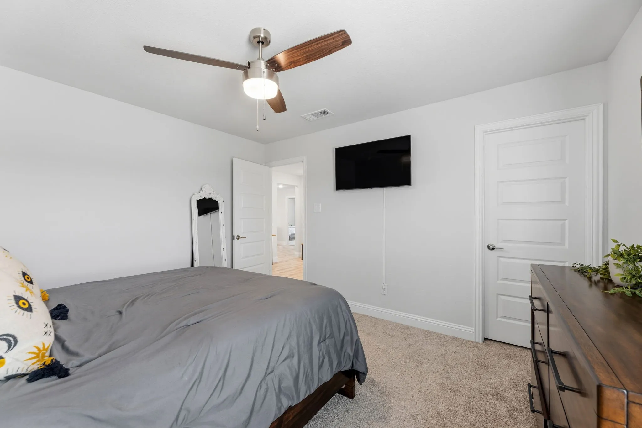 Carpeted room featuring a ceiling fan with light, white paneled doors, and light-toned walls