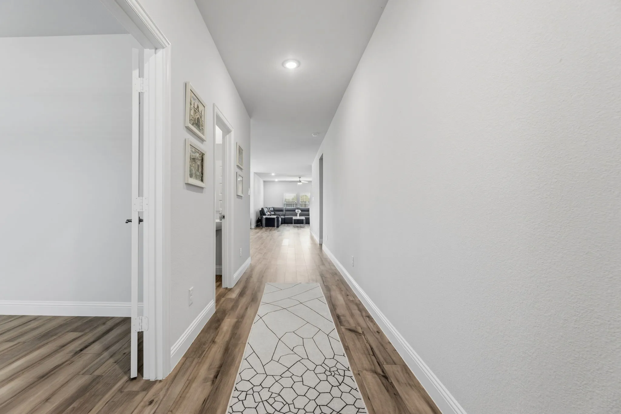 Long hallway with wood-finish flooring, light-colored walls, and recessed lighting