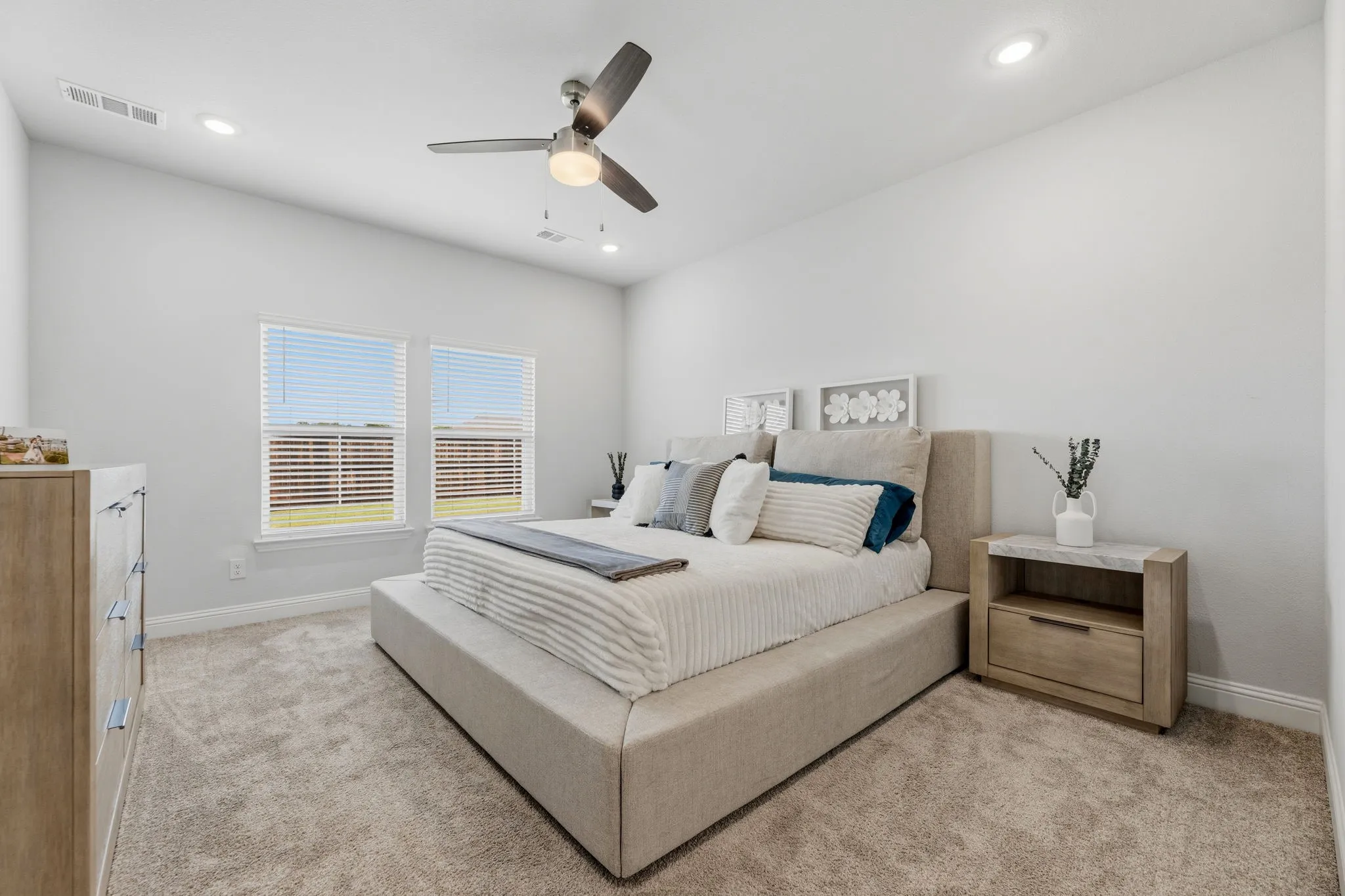 Spacious room featuring neutral carpeting, a ceiling fan with integrated lighting, recessed lighting, and two windows with blinds