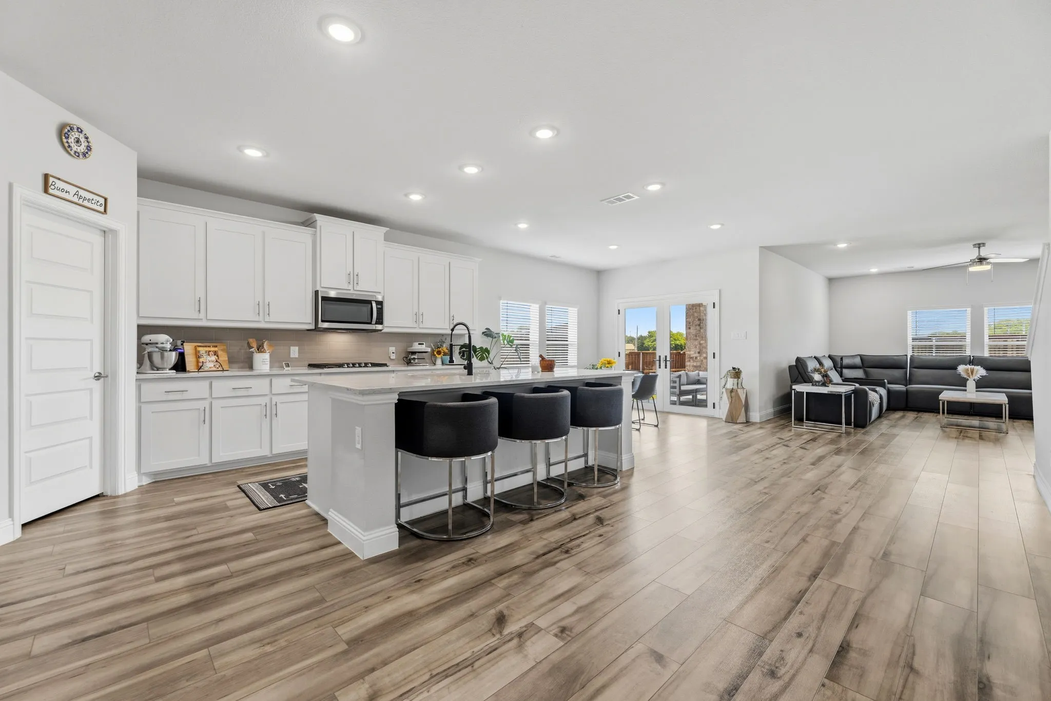 Open-concept living area featuring a kitchen island with seating, recessed lighting, and wood-finish flooring