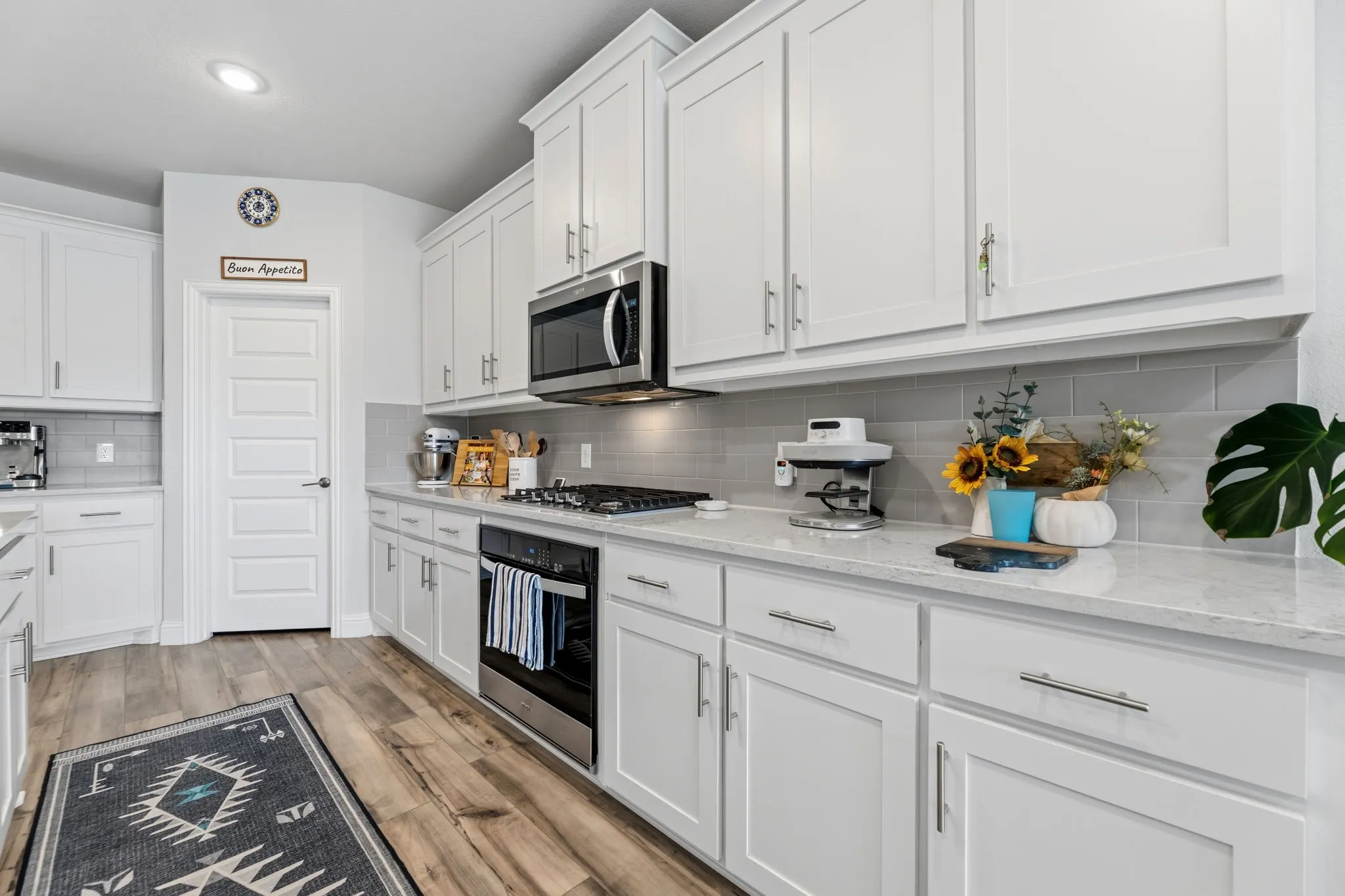 Modern kitchen featuring white shaker-style cabinetry, a light-toned countertop, and a gray subway tile backsplash