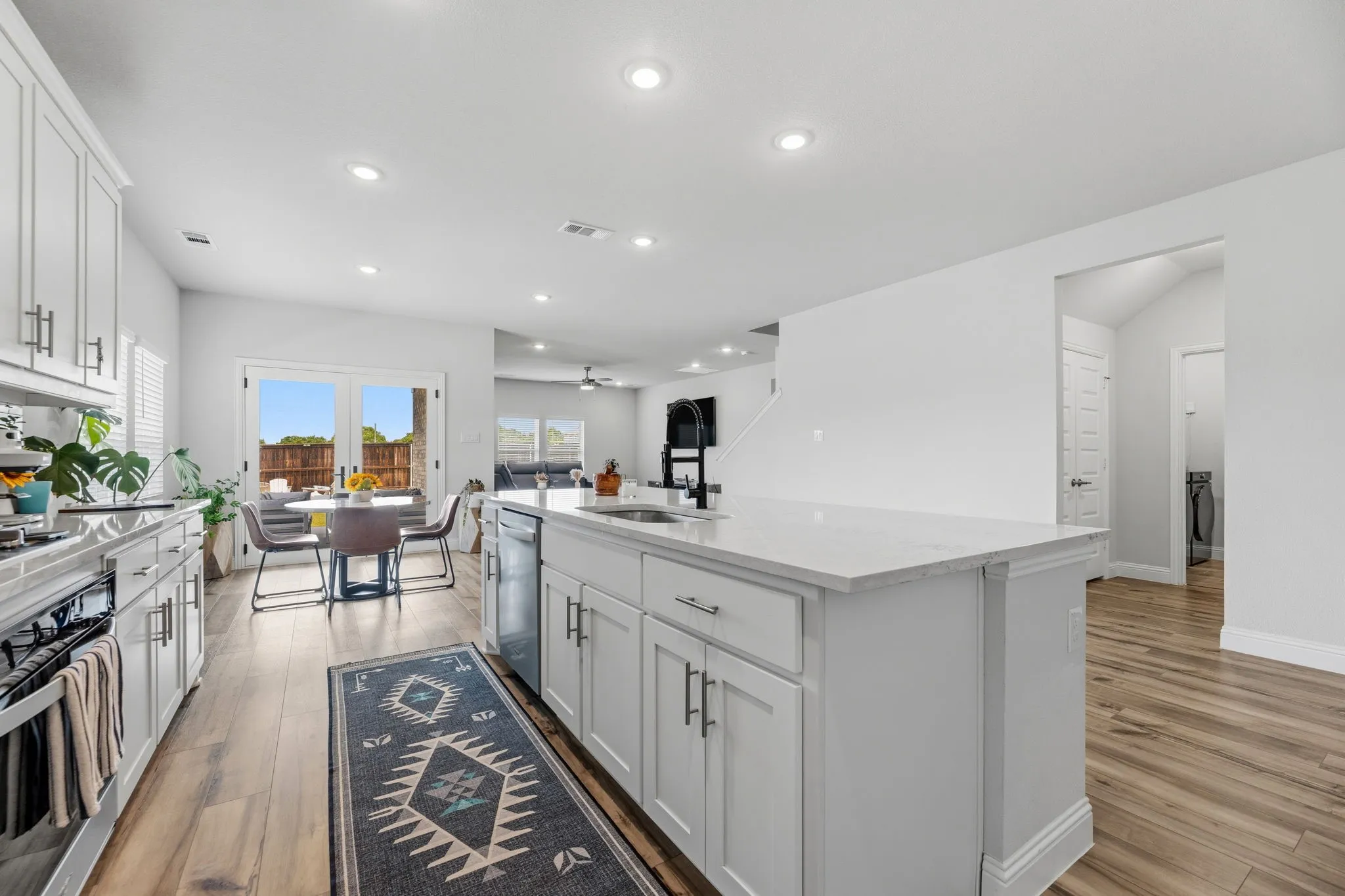 Contemporary kitchen featuring white cabinetry, a large kitchen island with a white countertop, recessed lighting, wood-finish flooring, and French doors leading to an outdoor space