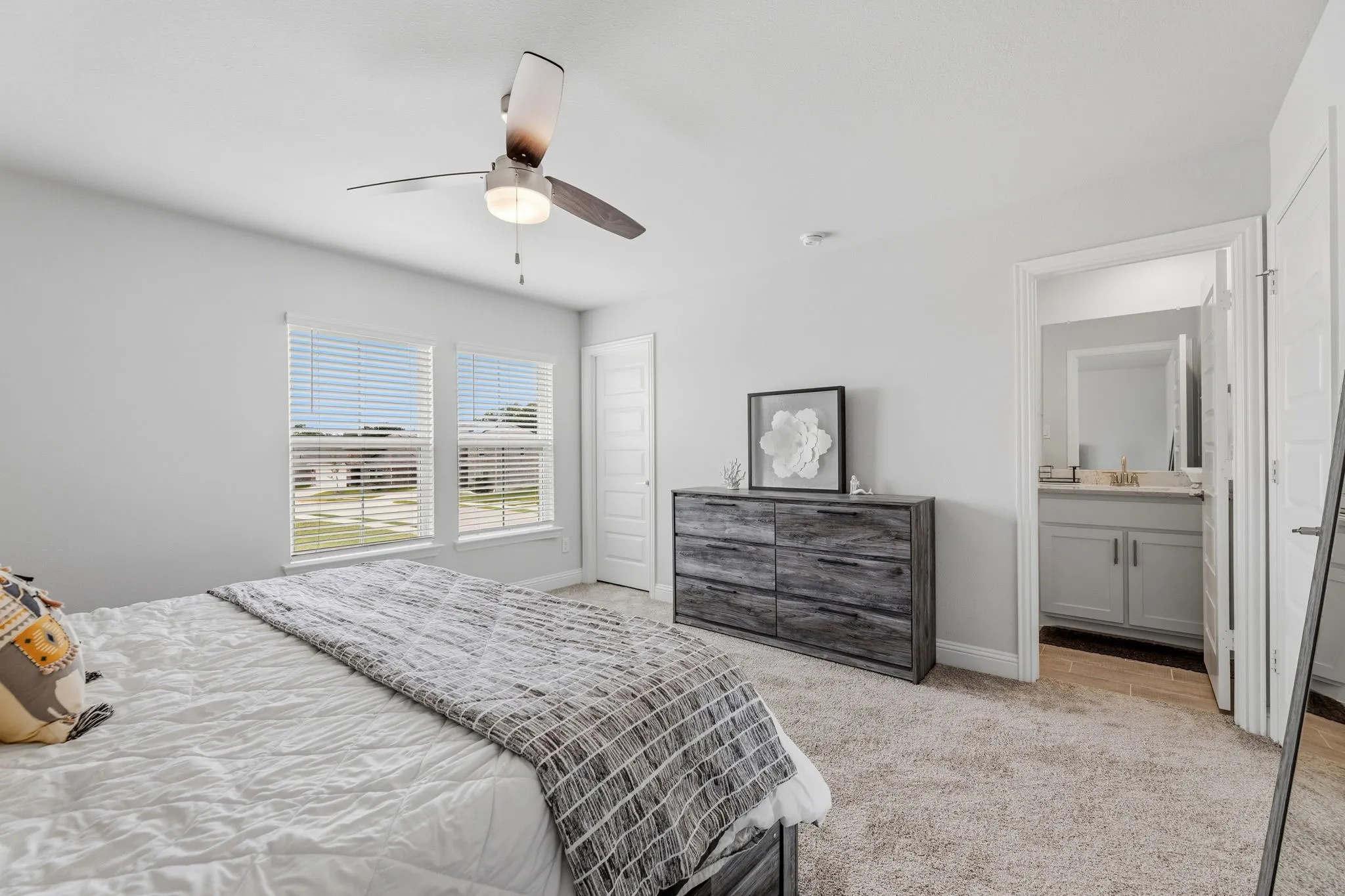 Bedroom featuring plush carpet flooring, a ceiling fan with integrated lighting, and two large windows with blinds