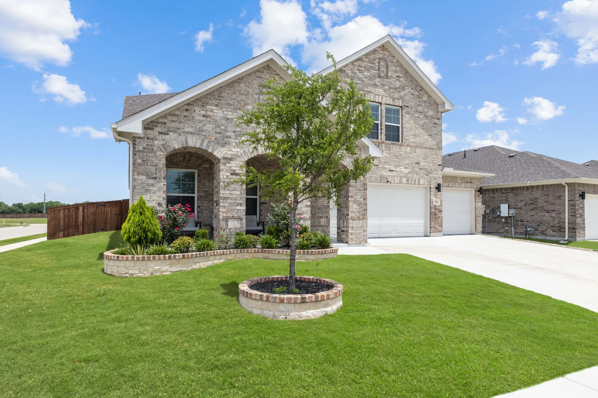 Stone façade residence featuring a two-car garage, concrete driveway, and covered entry porch