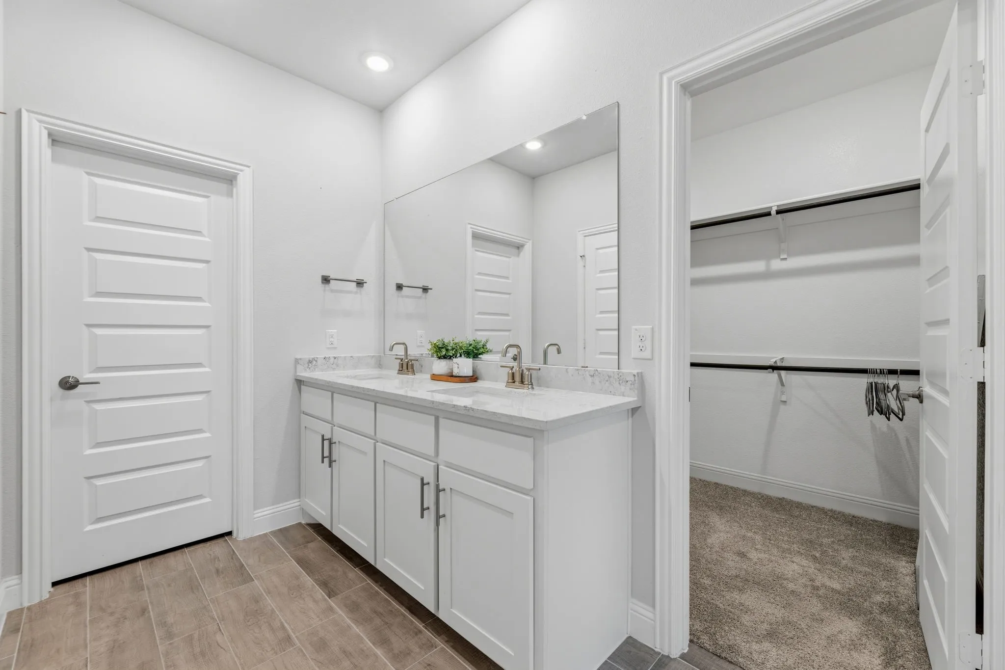 Dual sink vanity with white cabinetry, light-colored countertops, and brushed brass fixtures